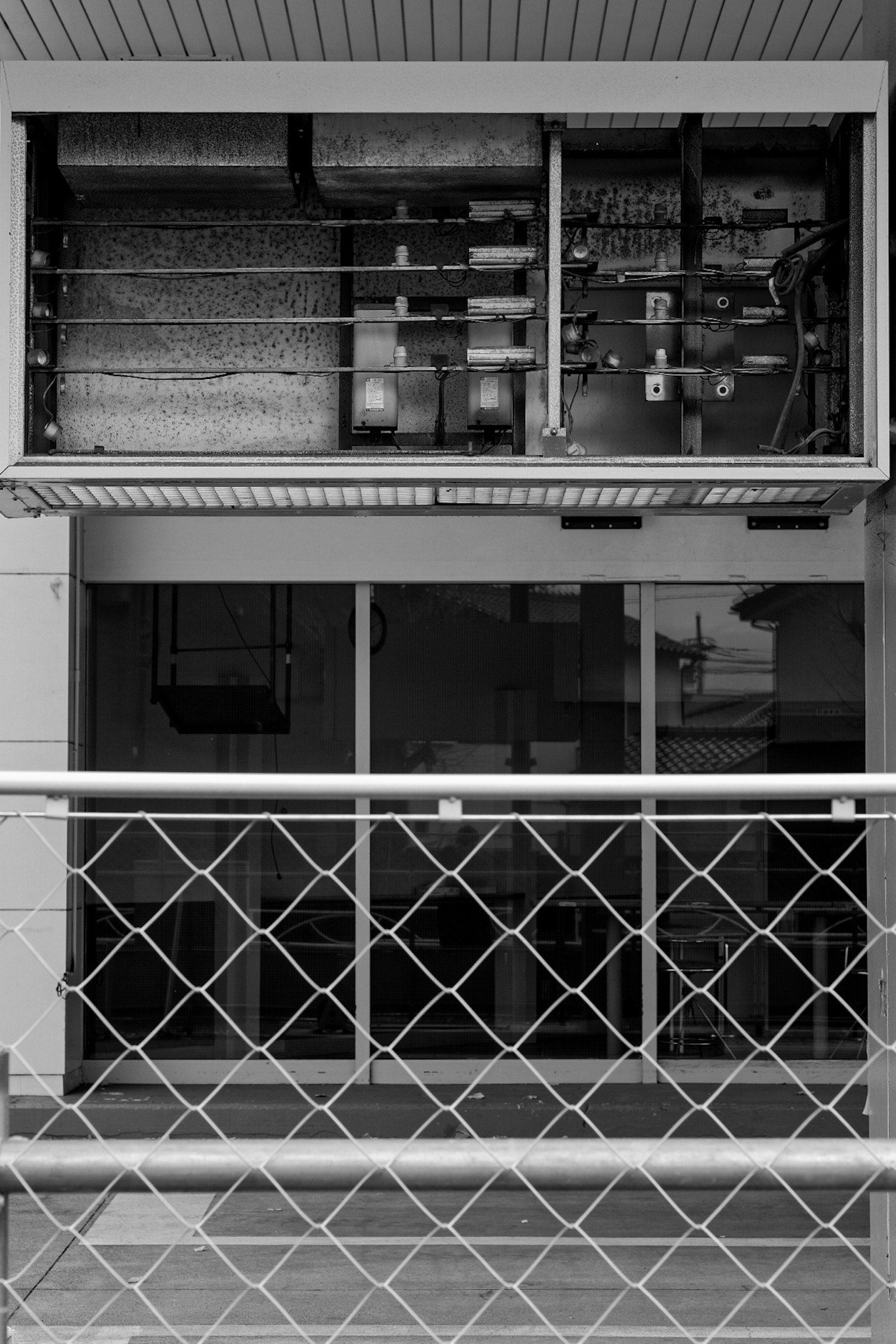 Black and white exterior of a building featuring electrical equipment and glass windows