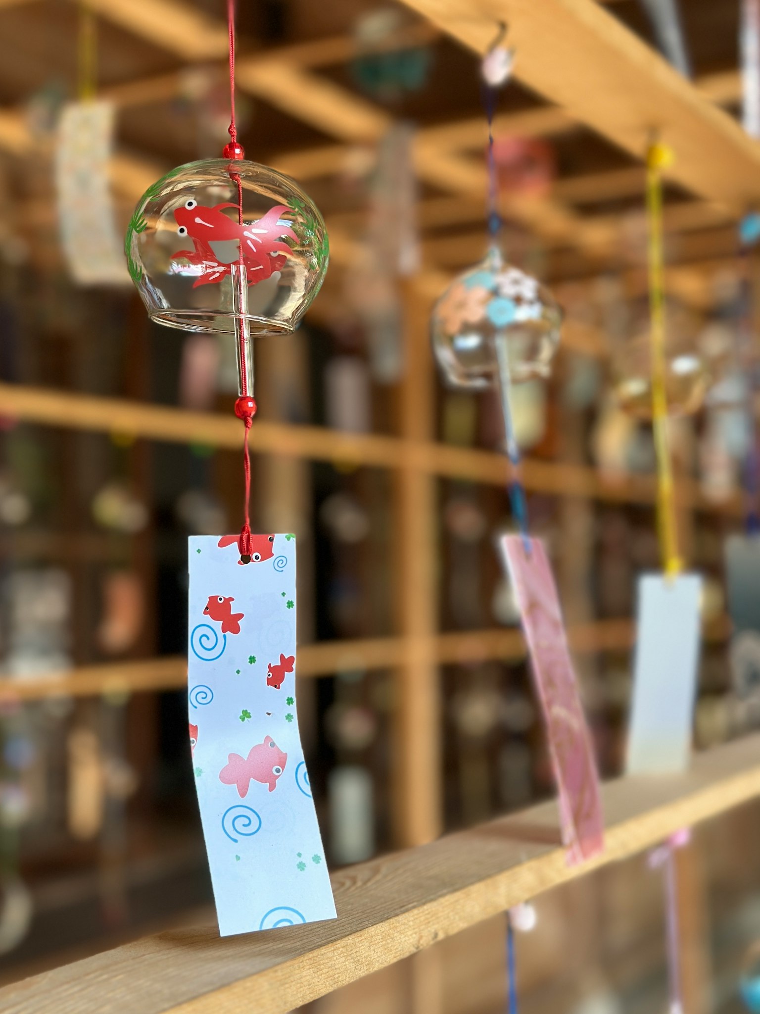 Colorful wind chimes and tanzaku hanging from a wooden shelf