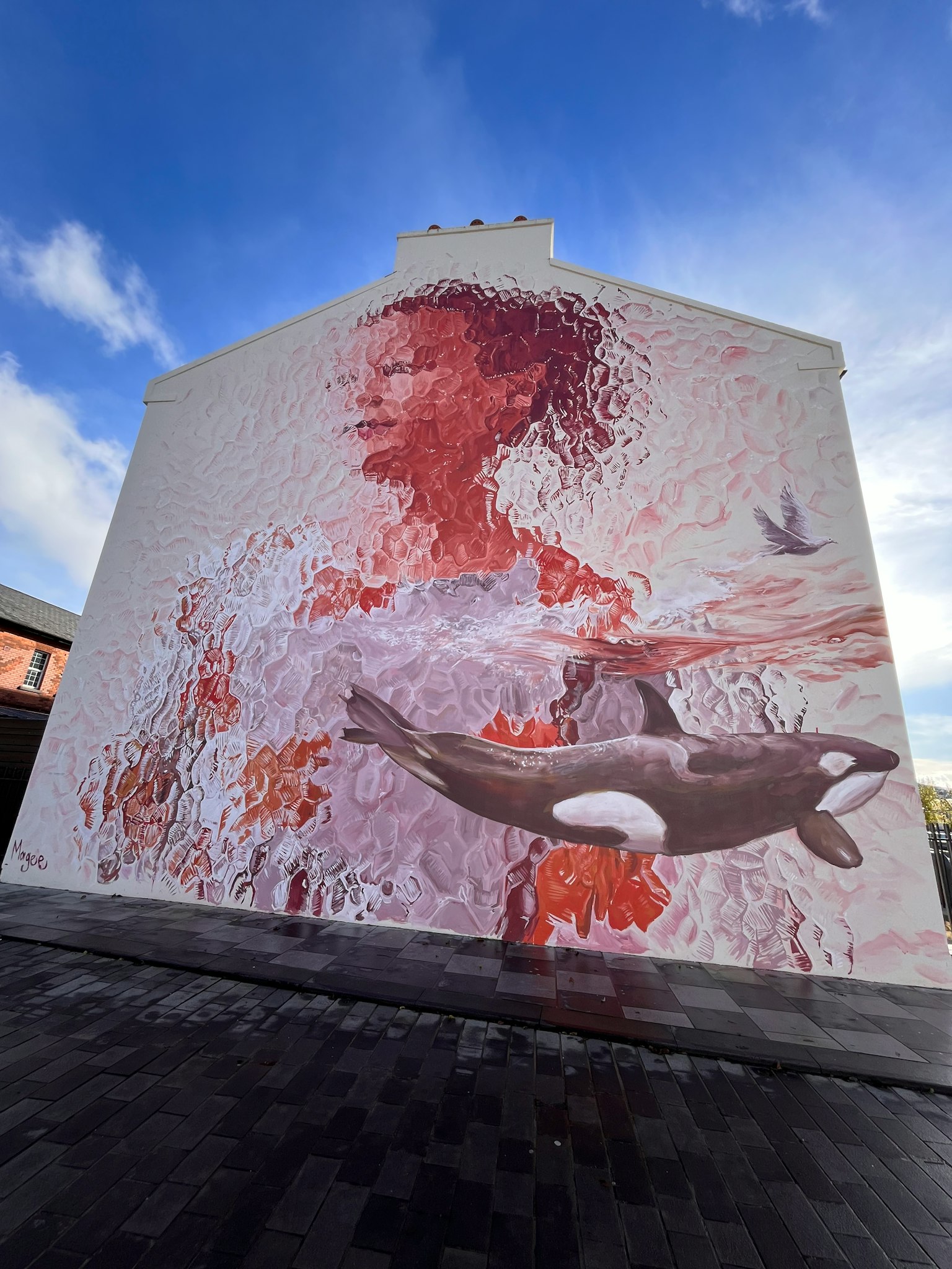 Murale che rappresenta una donna e un'orca in colori vivaci