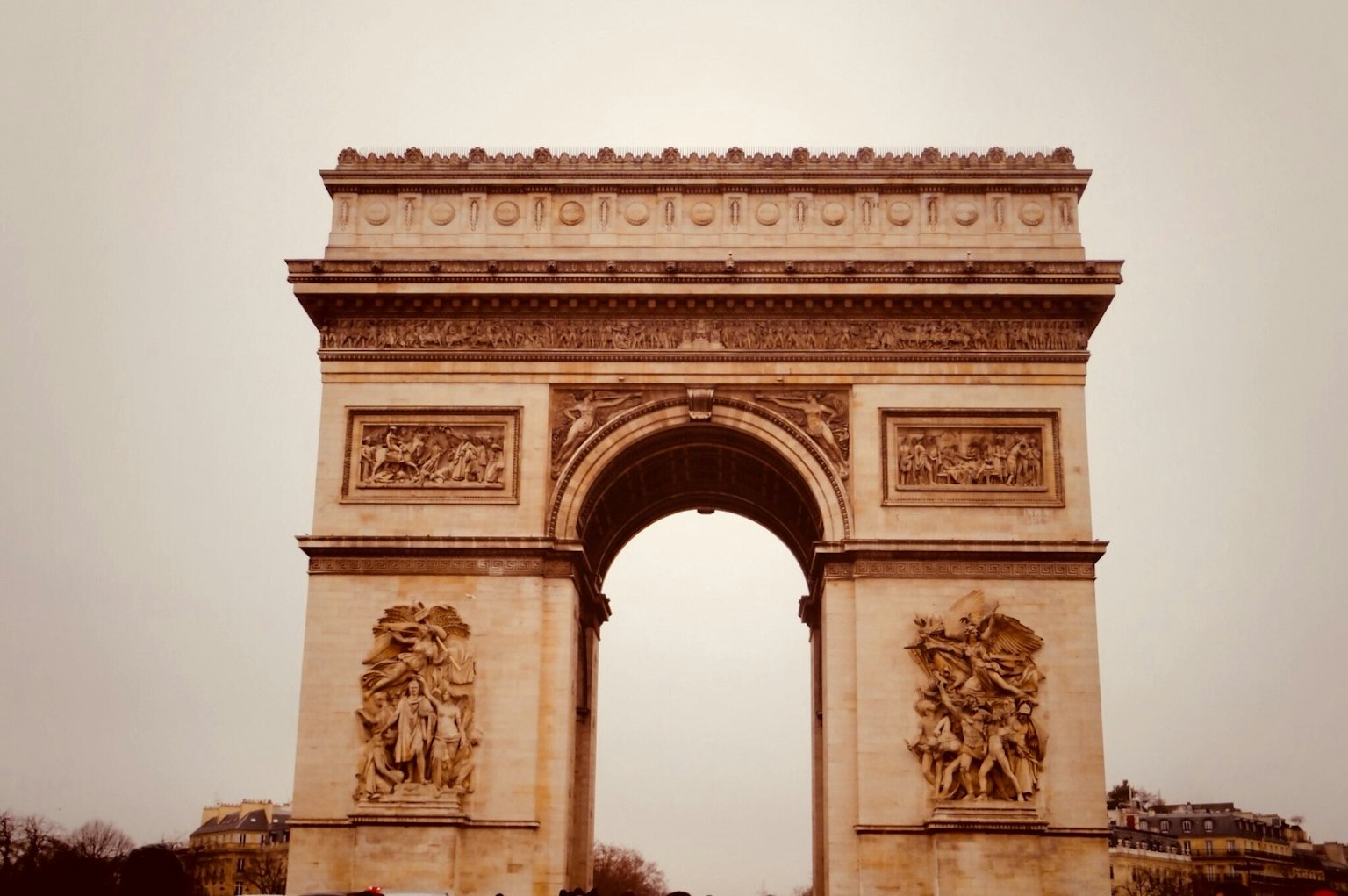 Vue de face de l'Arc de Triomphe à Paris montrant des sculptures historiques et une palette de couleurs douce
