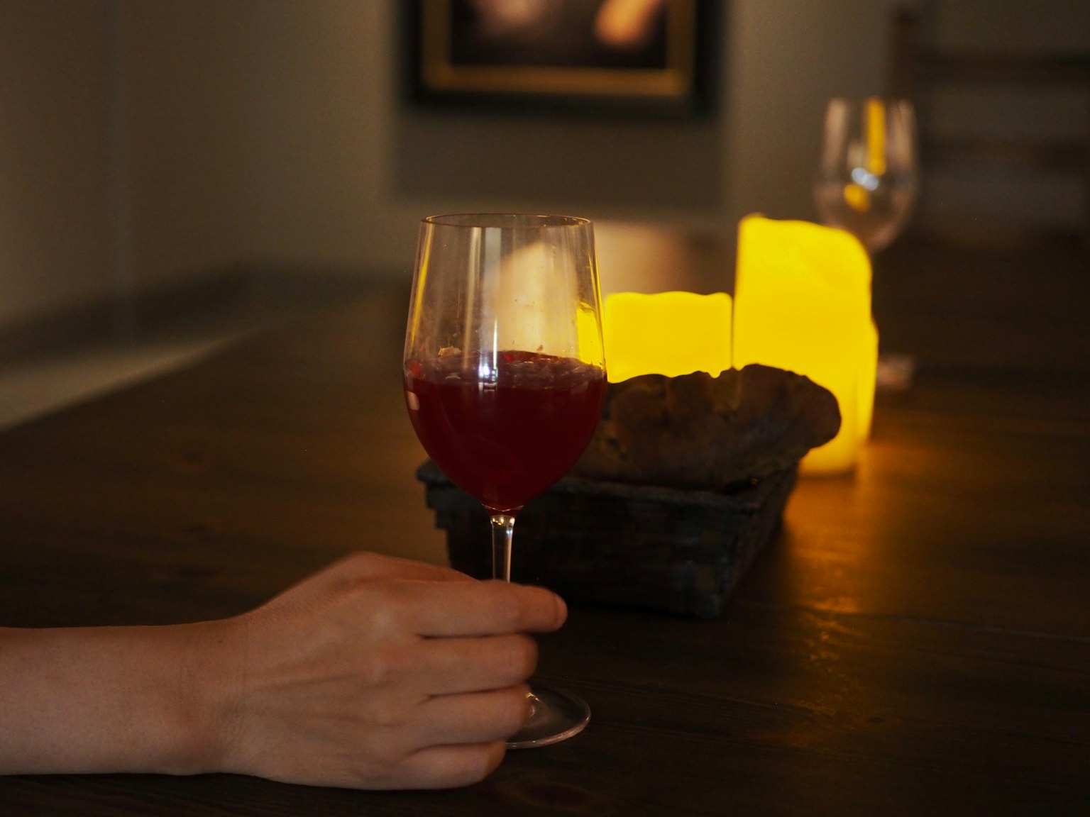 Un bicchiere di bevanda rossa su un tavolo con candele luminose