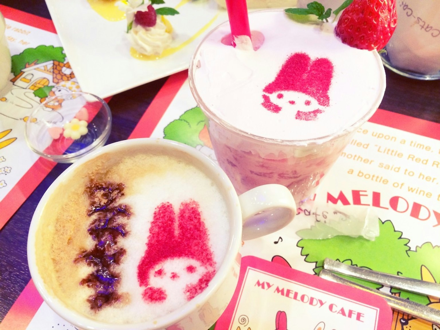 Cà phê cappuccino và đồ uống dâu tây có nghệ thuật latte hình nhân vật trên bàn cà phê