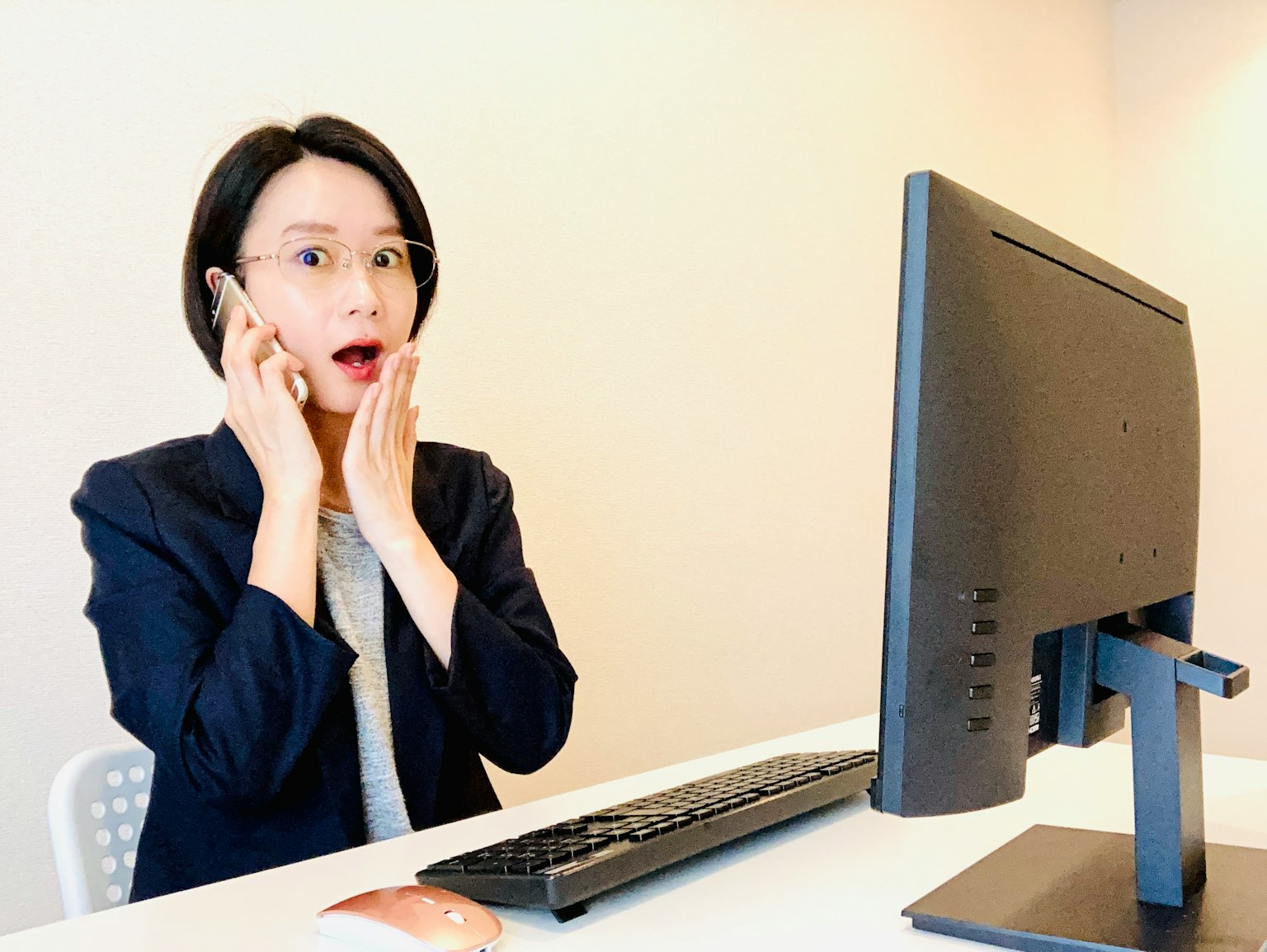 Wanita dengan ekspresi terkejut duduk di depan komputer