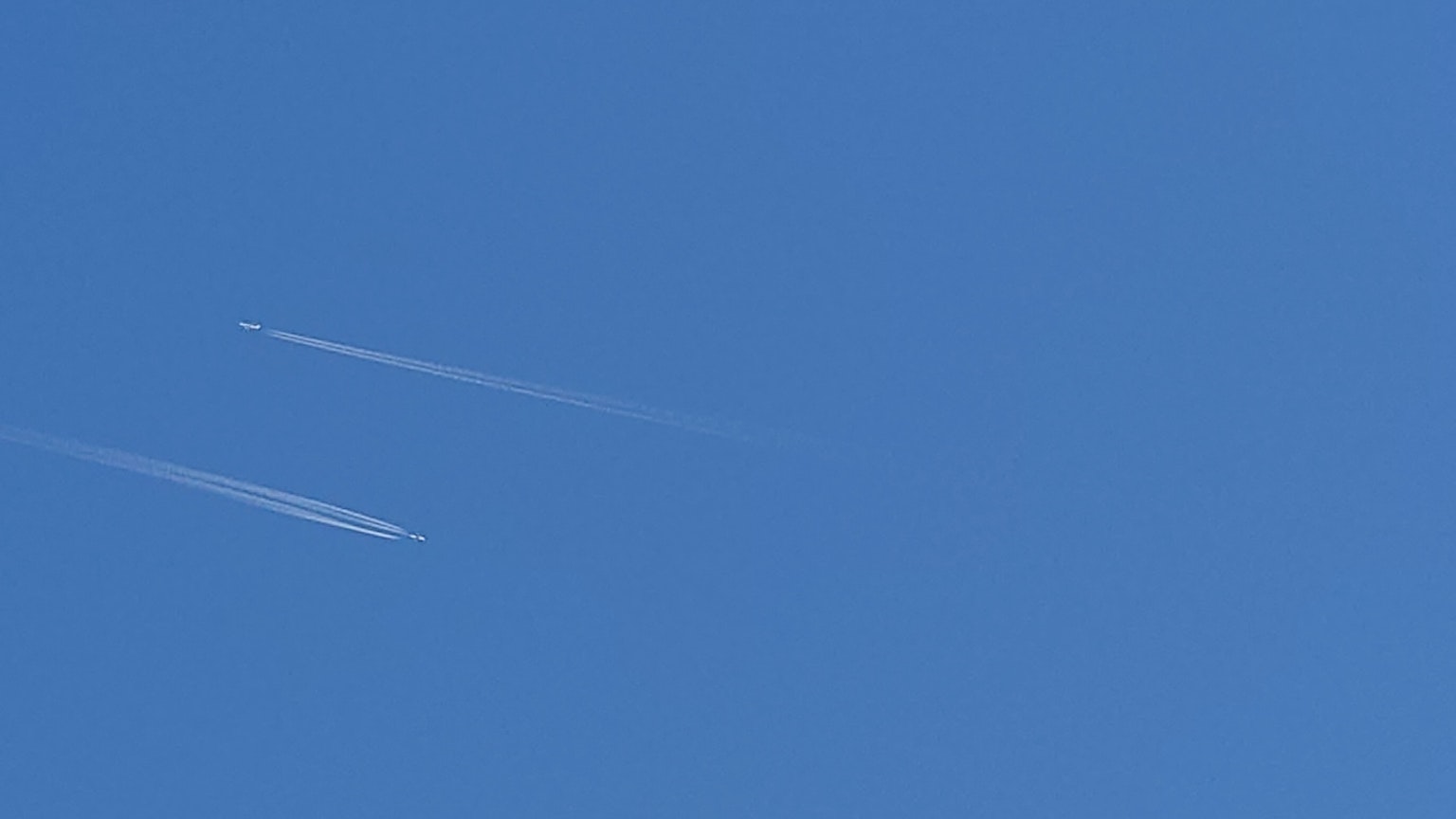 Jejak pesawat terlihat di langit biru yang cerah