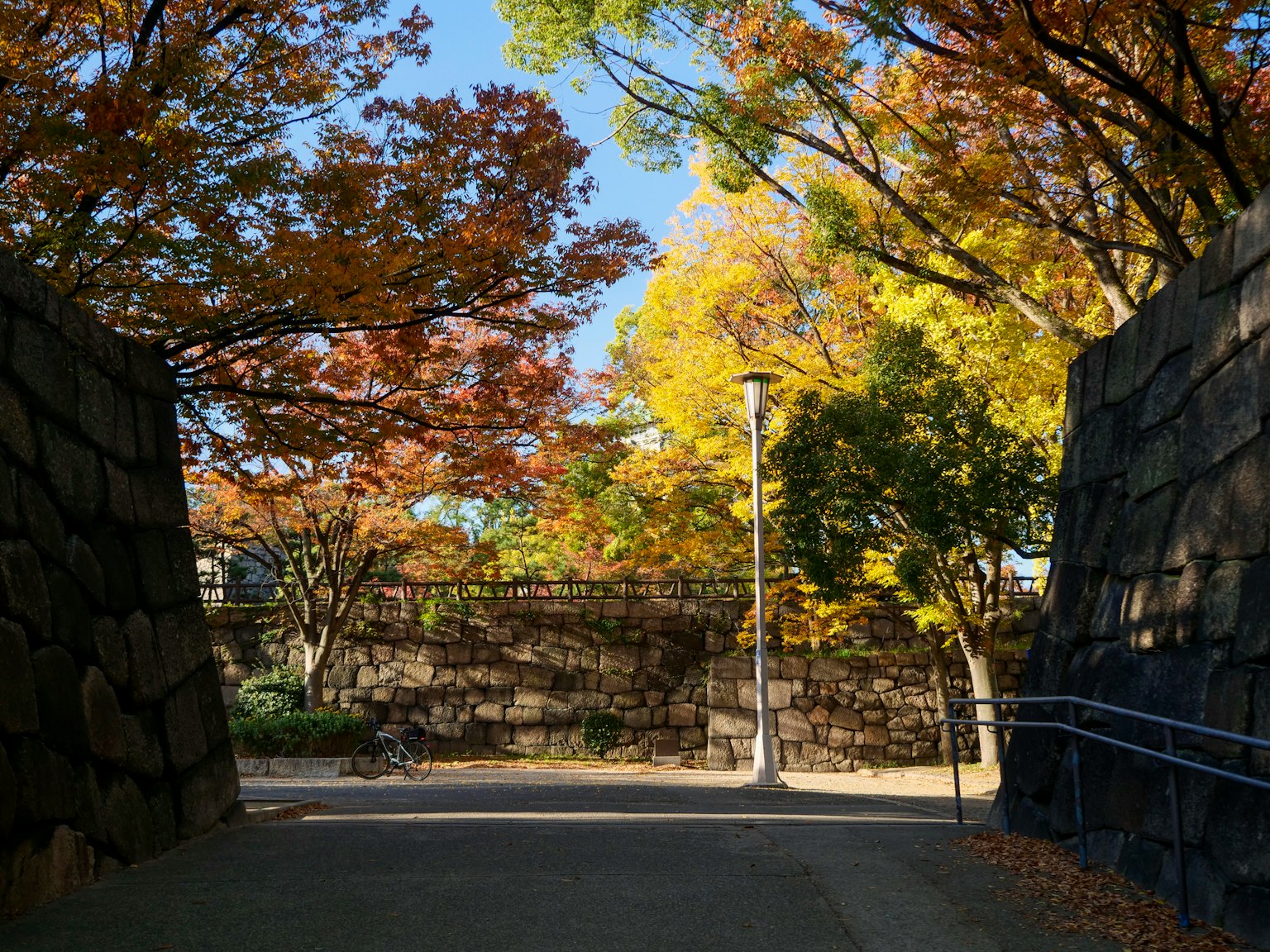 秋天色彩環繞的公園入口，黃色和橙色的樹葉，石牆