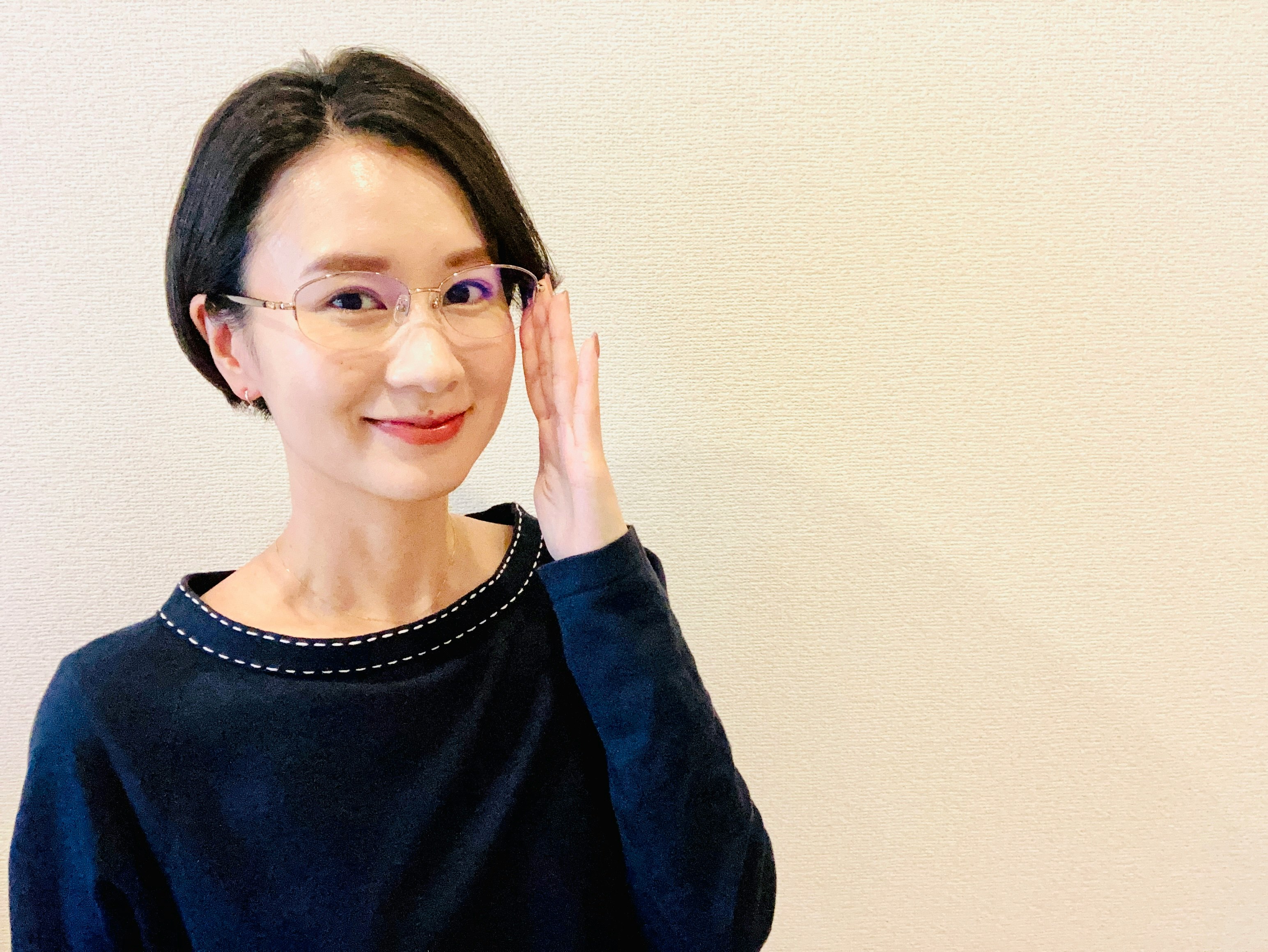 手を頬に添えたメガネの女性のポートレート
