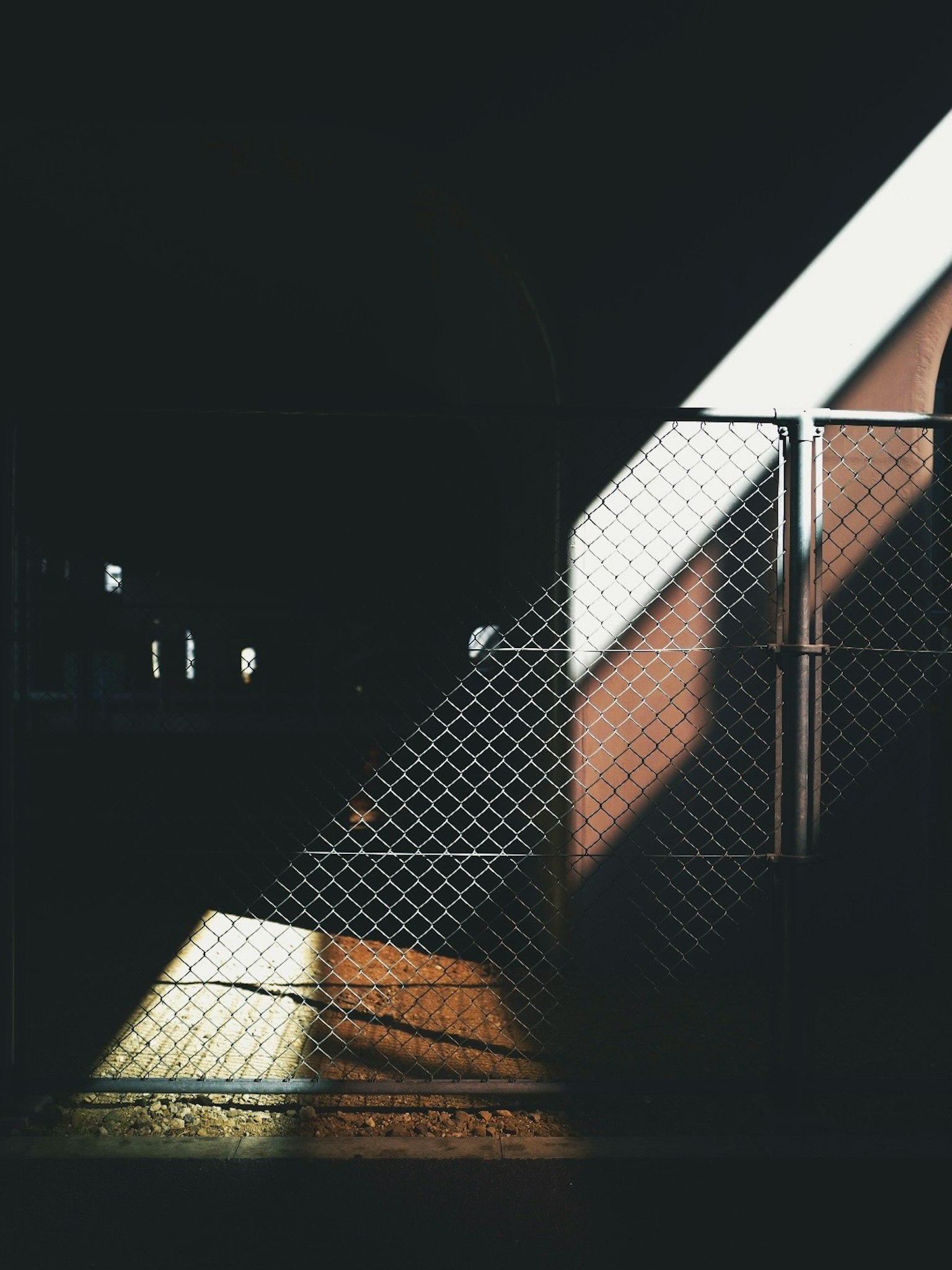 暗い背景に対する光の斜めの線と金網のフェンス