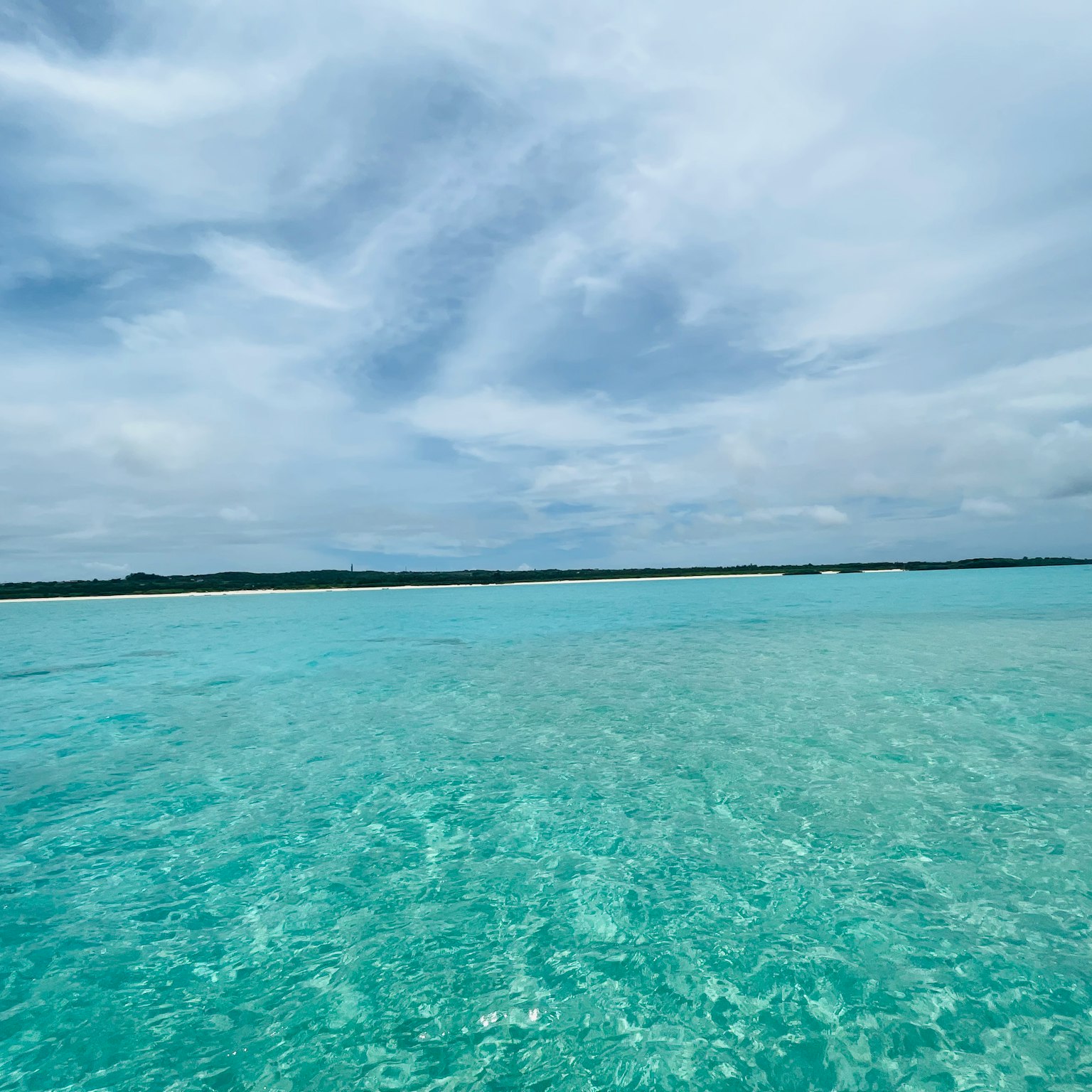 Lanskap luas dengan air berwarna turquoise dan langit mendung
