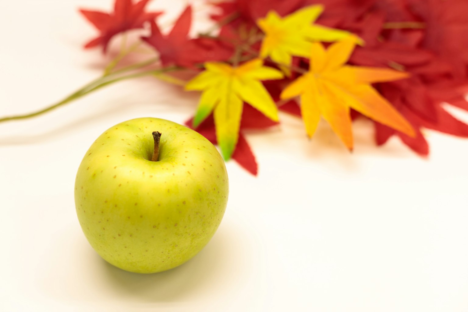 Pomme verte avec des feuilles d'automne rouges et jaunes