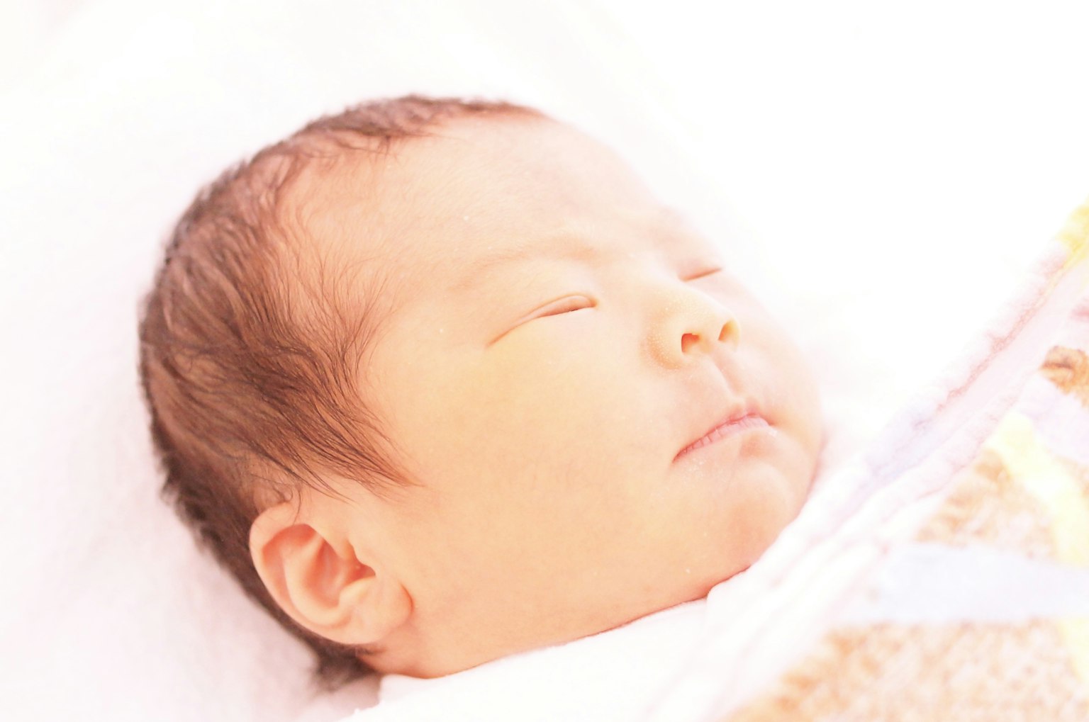 Seorang bayi tidur nyenyak dengan latar belakang cerah dan selimut lembut