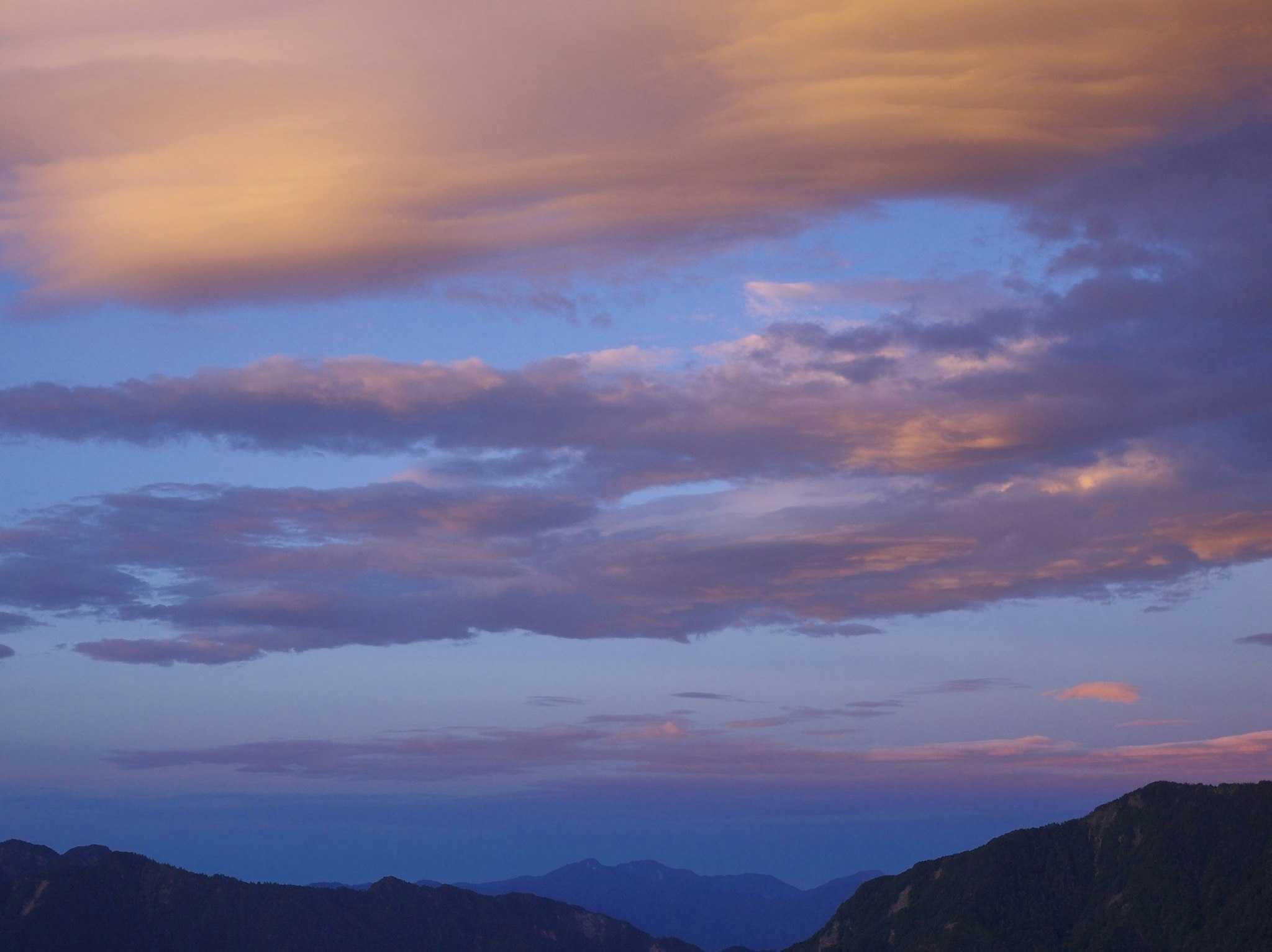 夕焼けの空に広がる雲と山並み