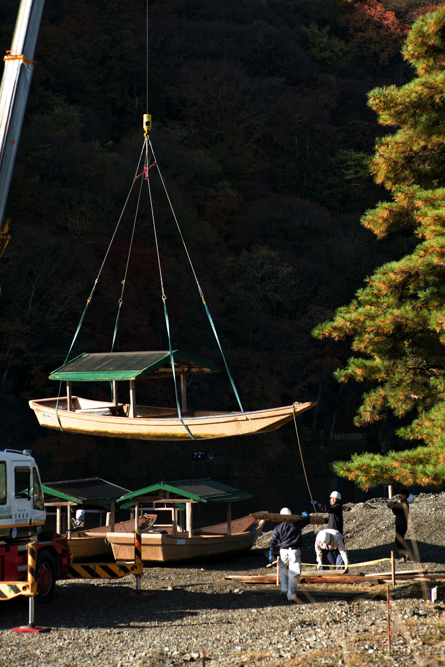 Traditional Japanese boat being lifted by a crane with workers present