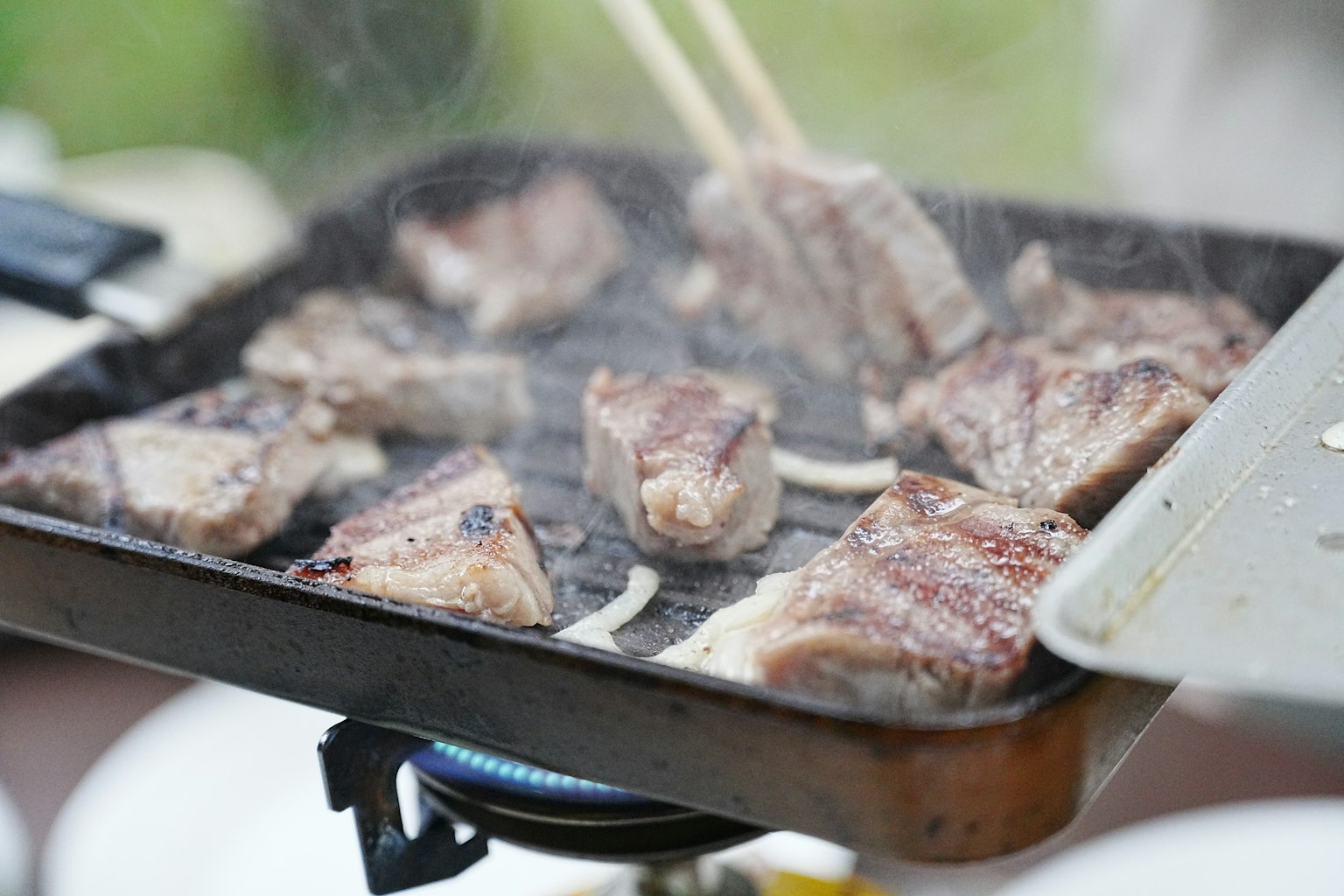 Carne che cuoce su una griglia con fumi che salgono