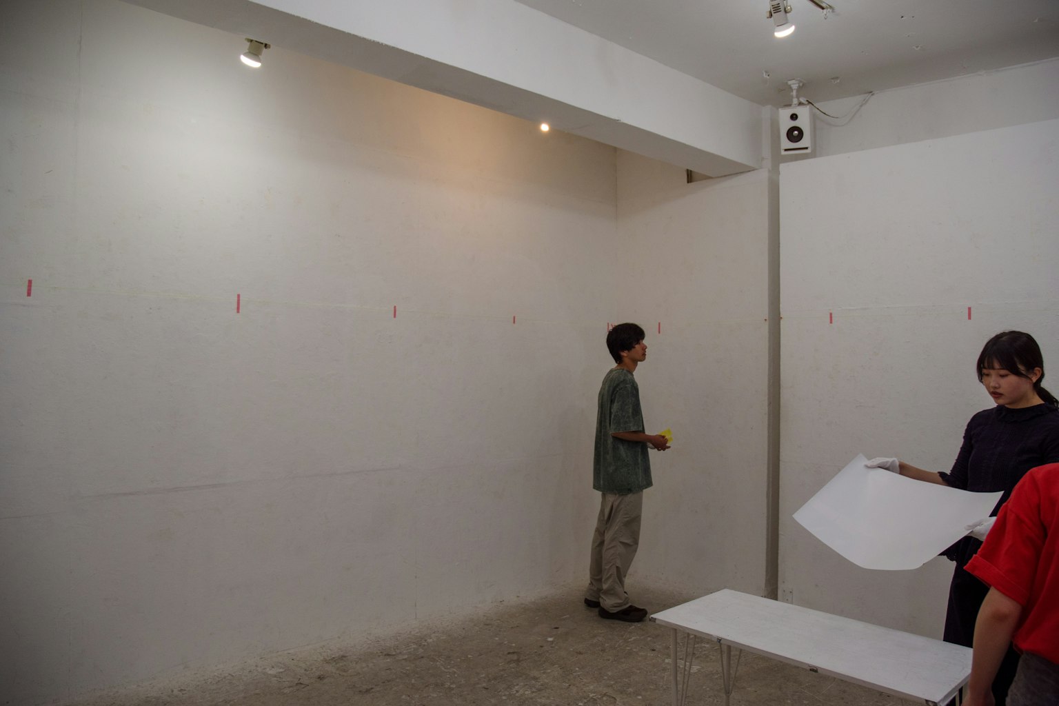 白い壁の前で作業する二人の人物と空間