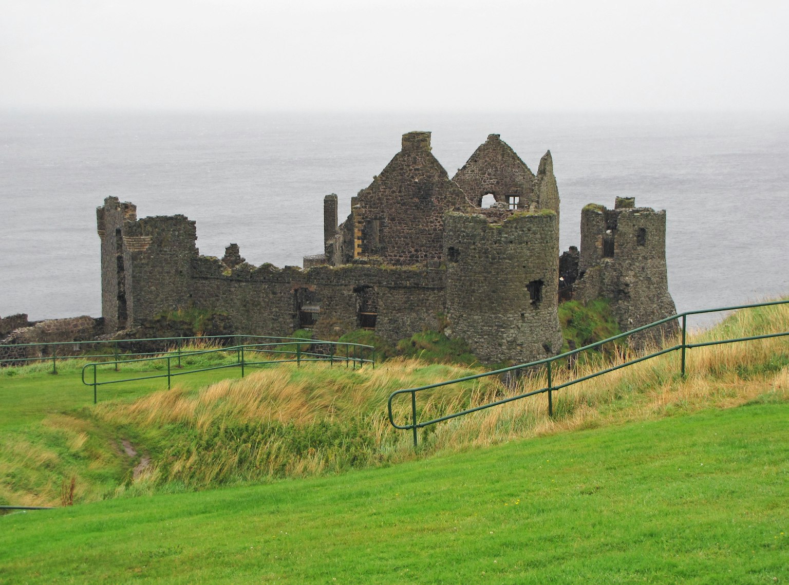 Rovine di un antico castello che si affaccia sul mare circondate da erba verde