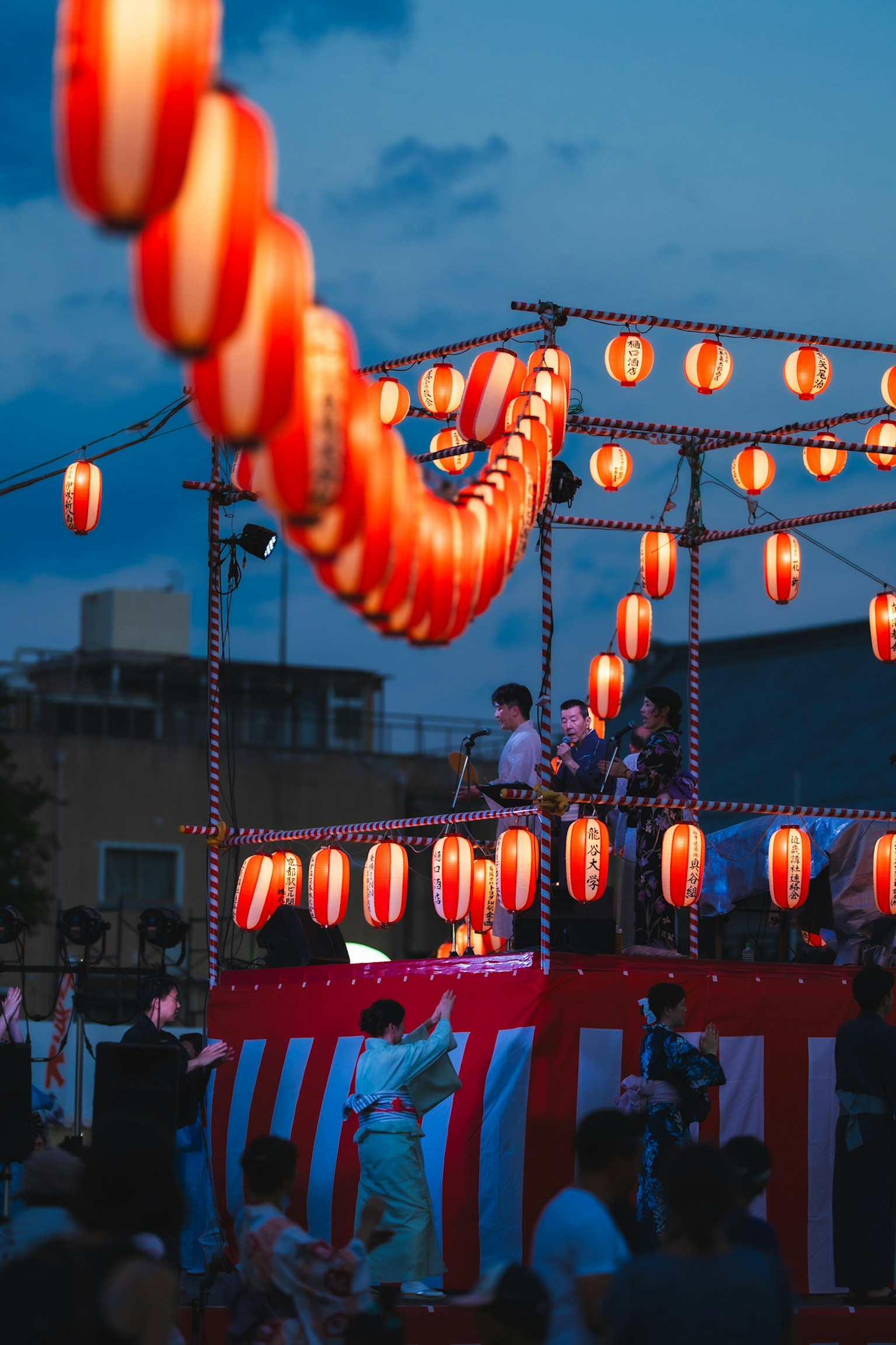 Festival scene at dusk with red lanterns hanging People gathered and dancing