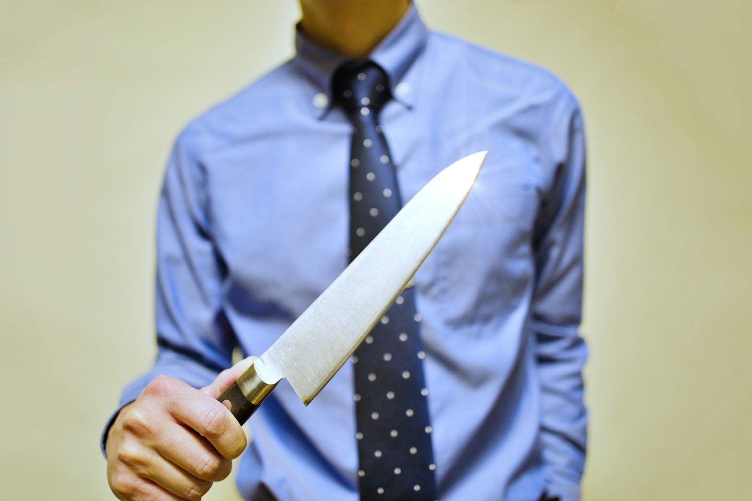 穿着蓝色衬衫的男人手持刀具