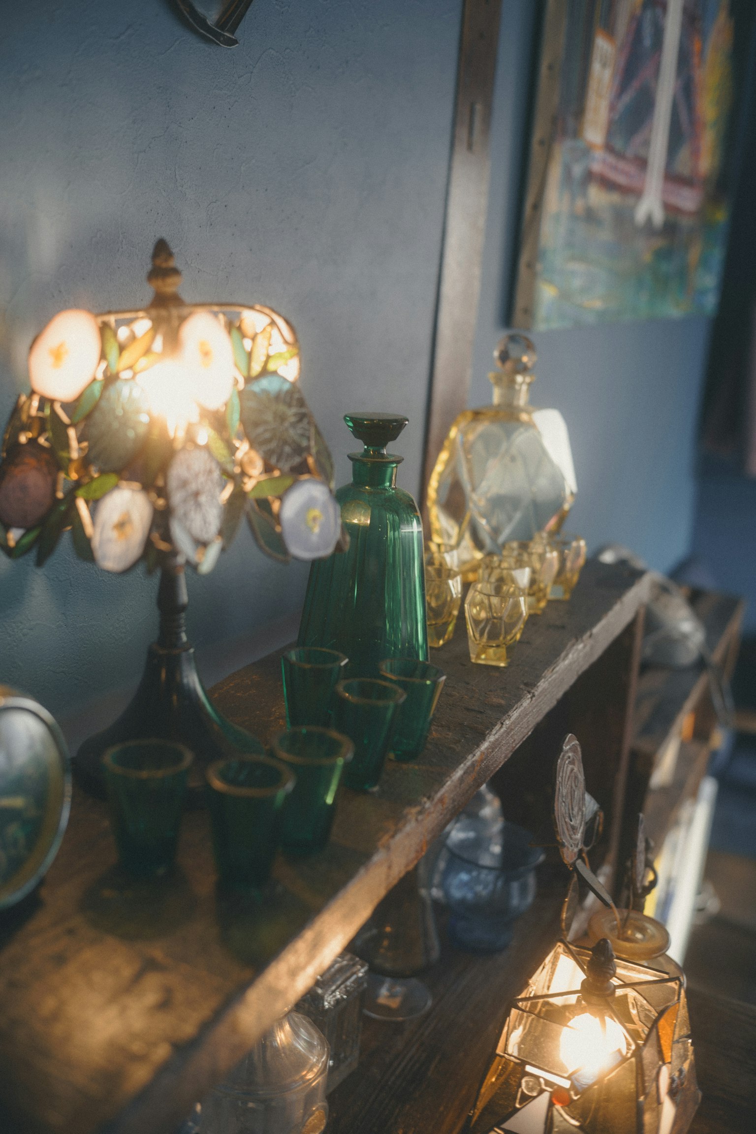 色とりどりのアンティークランプとガラス製の装飾品が並ぶ棚の画像