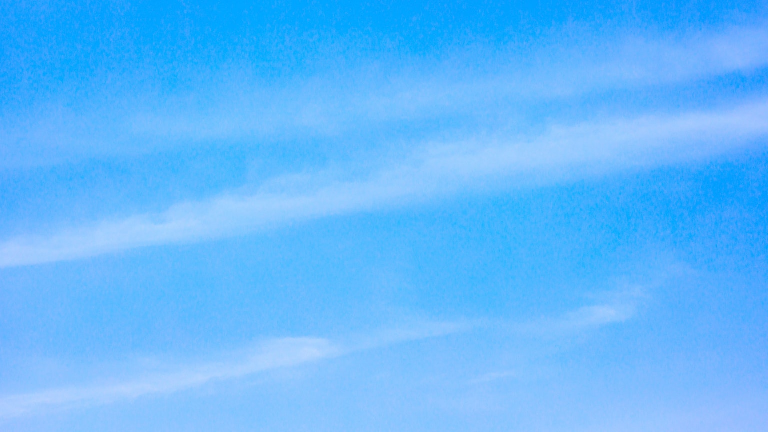 A clear blue sky with soft white clouds