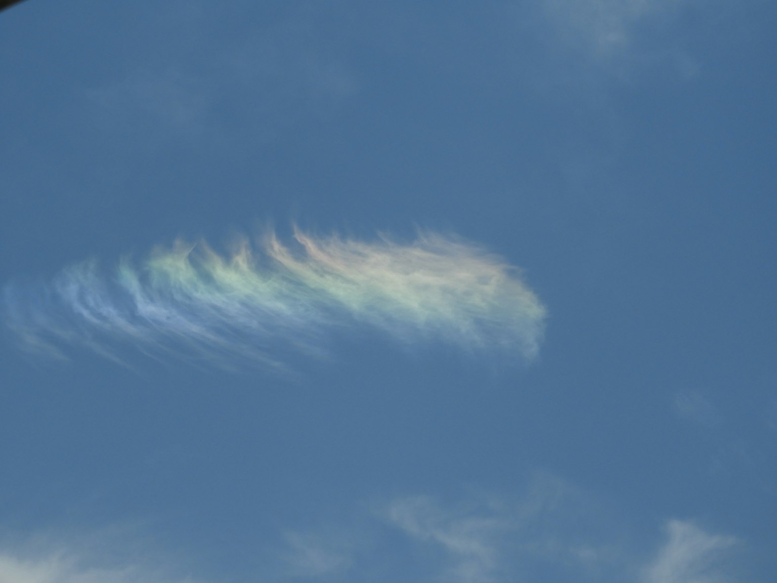 Ein Streifen irideszenter Wolken in einem blauen Himmel