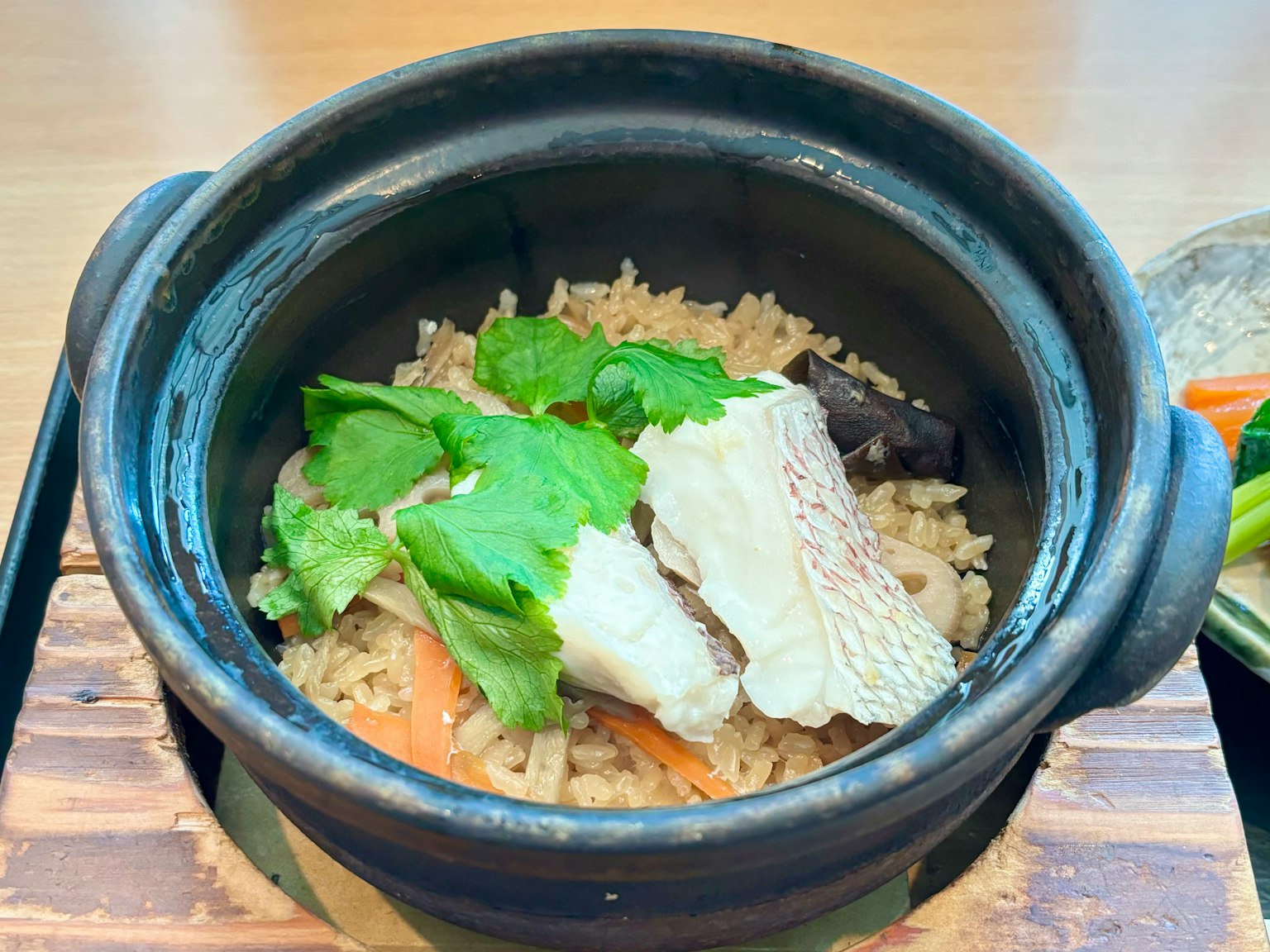 Plato de arroz servido en una olla de barro negra cubierto con pollo y verduras