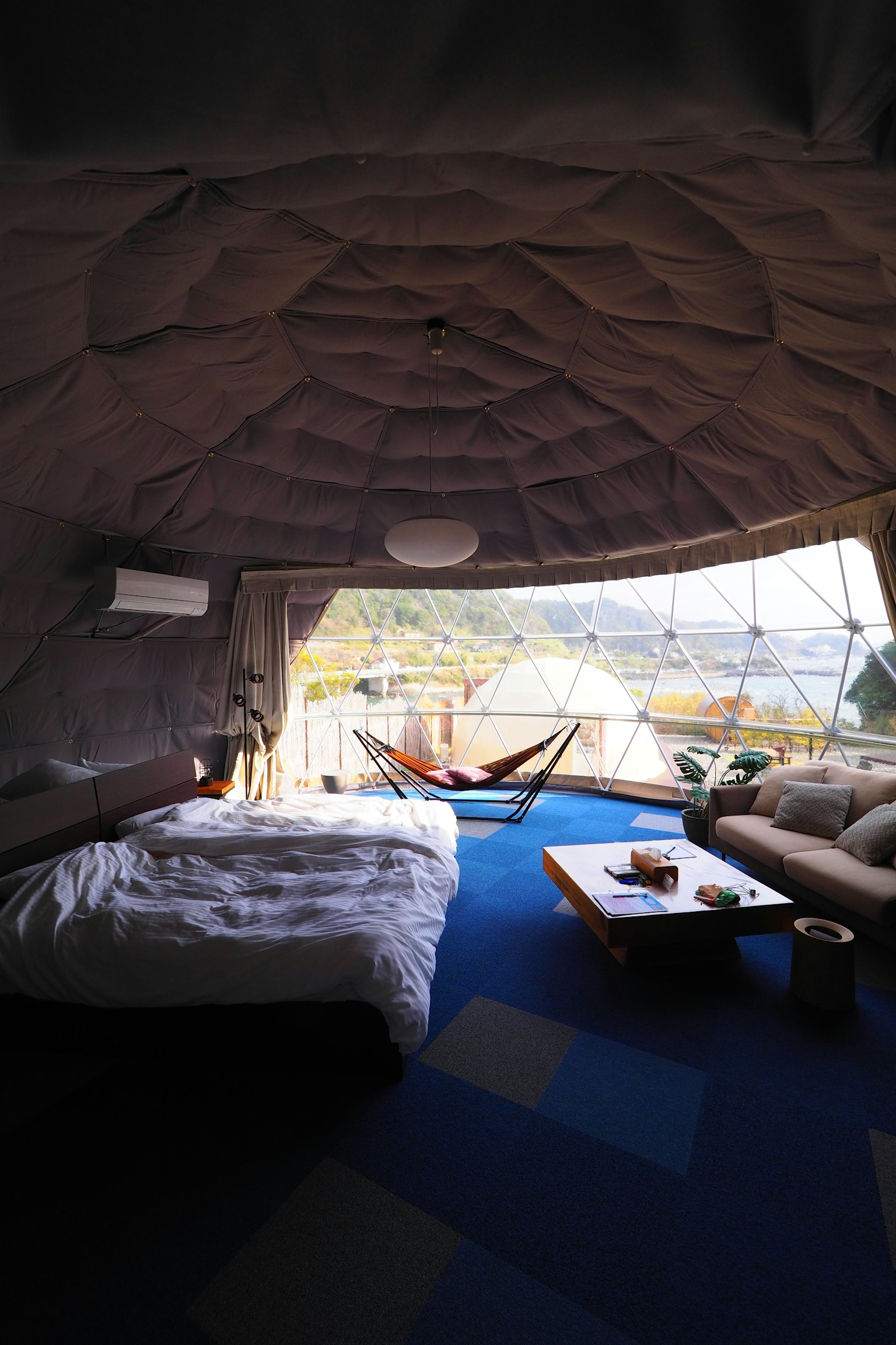 Interior of a unique dome-shaped accommodation featuring a bed and sofa