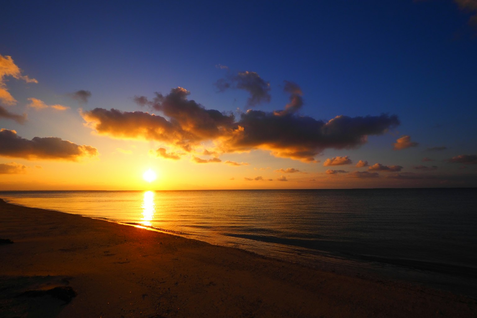 Escena de playa serena con un hermoso atardecer reflejándose en aguas tranquilas