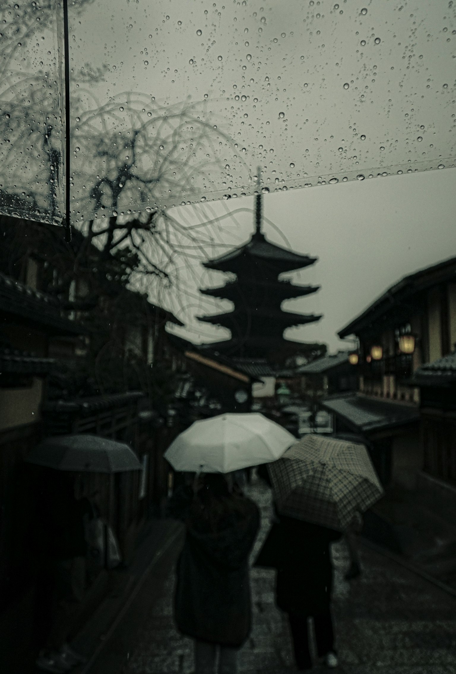 人们在雨中拿着伞走在靠近塔的地方