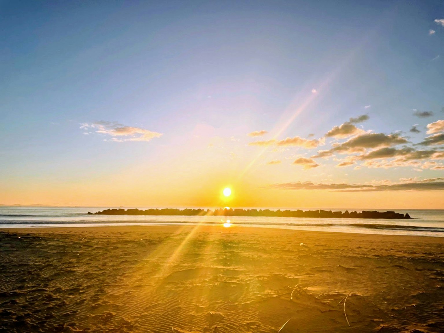 Bella scena di tramonto sulla spiaggia con tonalità arancioni e blu nel cielo e nell'oceano