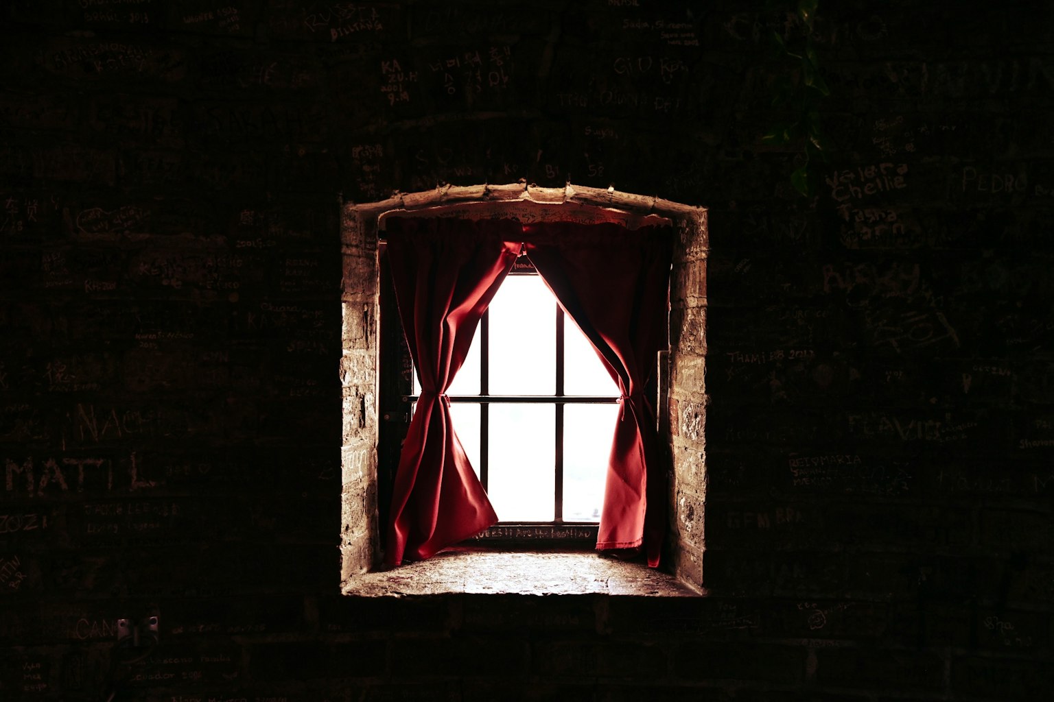 Immagine di una finestra con tende rosse su un muro scuro