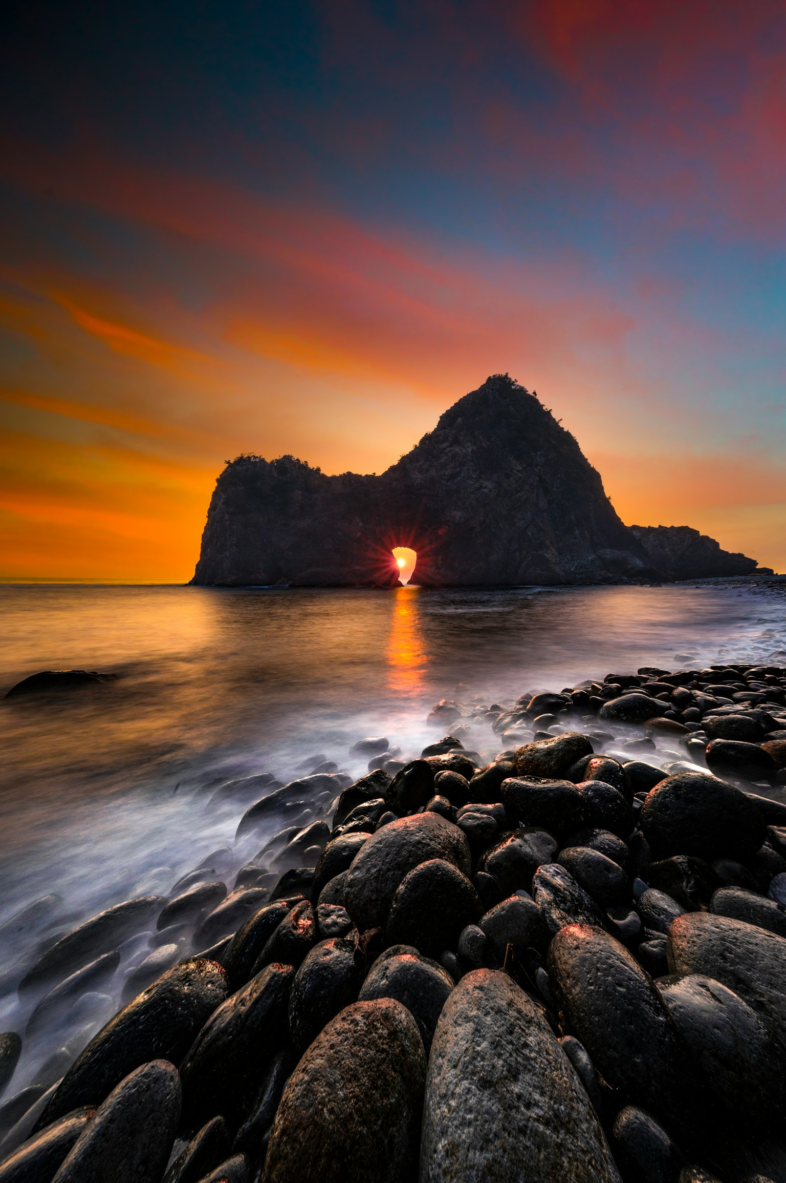 Beautiful beach landscape with sunset visible through rock formations