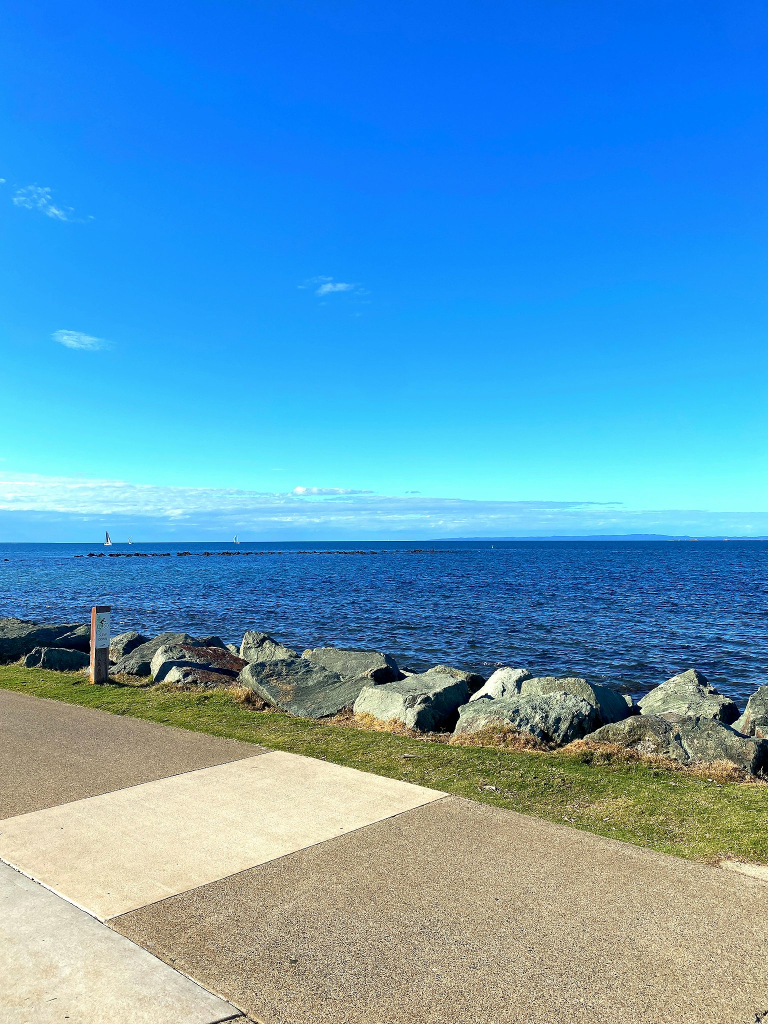 Faszinierende Aussicht auf einen blauen Himmel und den Ozean mit einem Steindeich und einem Weg