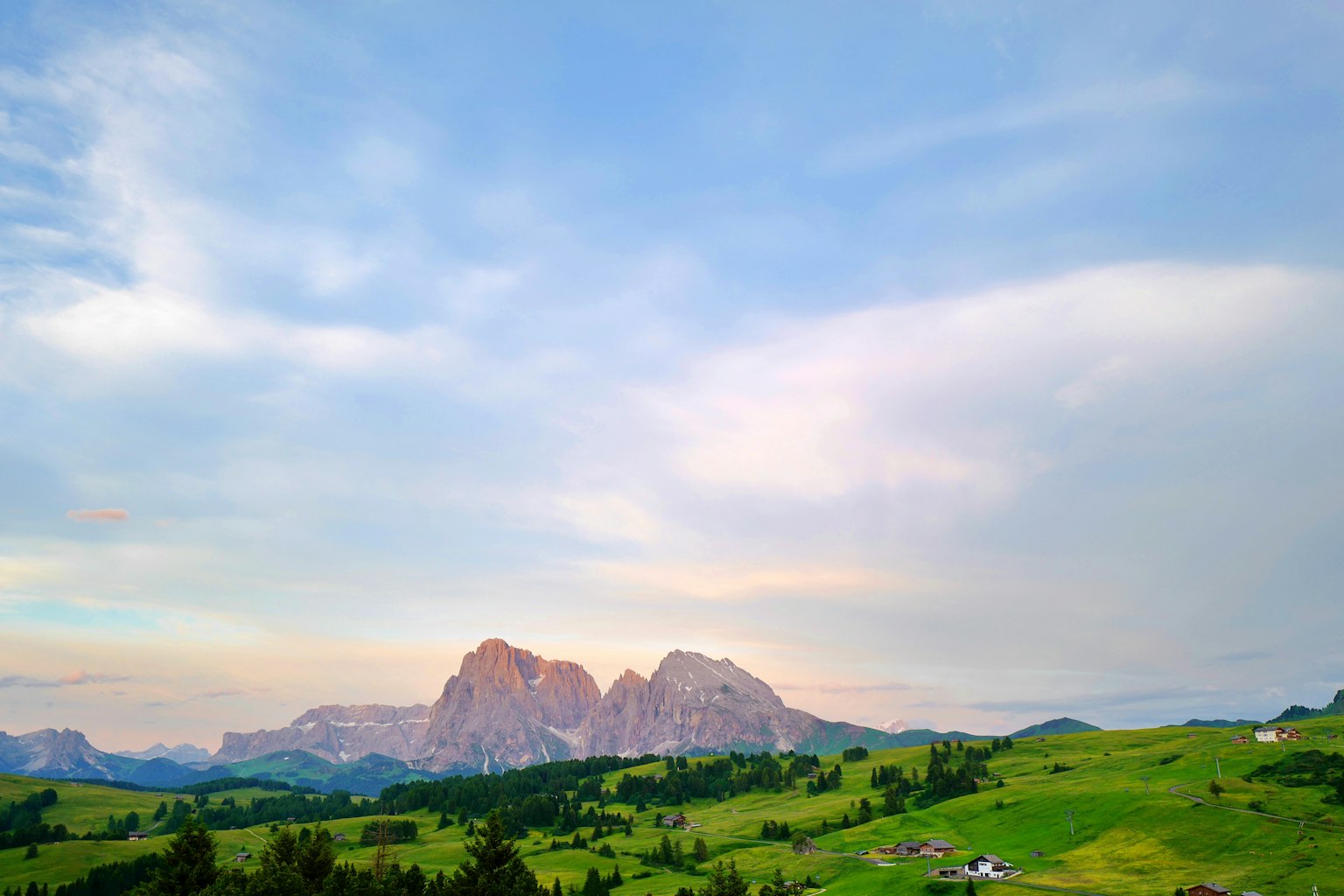Vue panoramique de montagnes et de prairies verdoyantes sous un ciel bleu