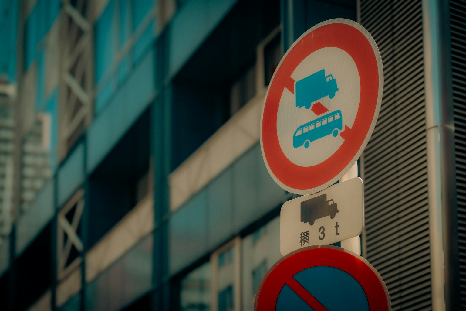 Panneaux de circulation interdisant le stationnement pour les camions et les bus à côté d'un bâtiment moderne bleu