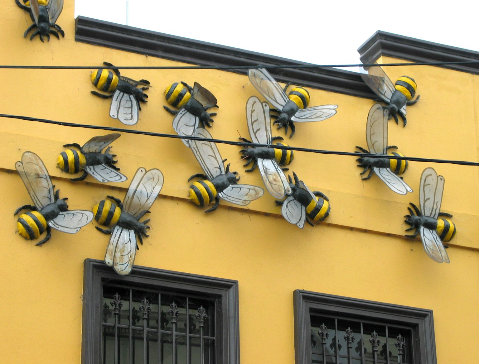 Grandes sculptures d'abeilles montées sur un mur jaune