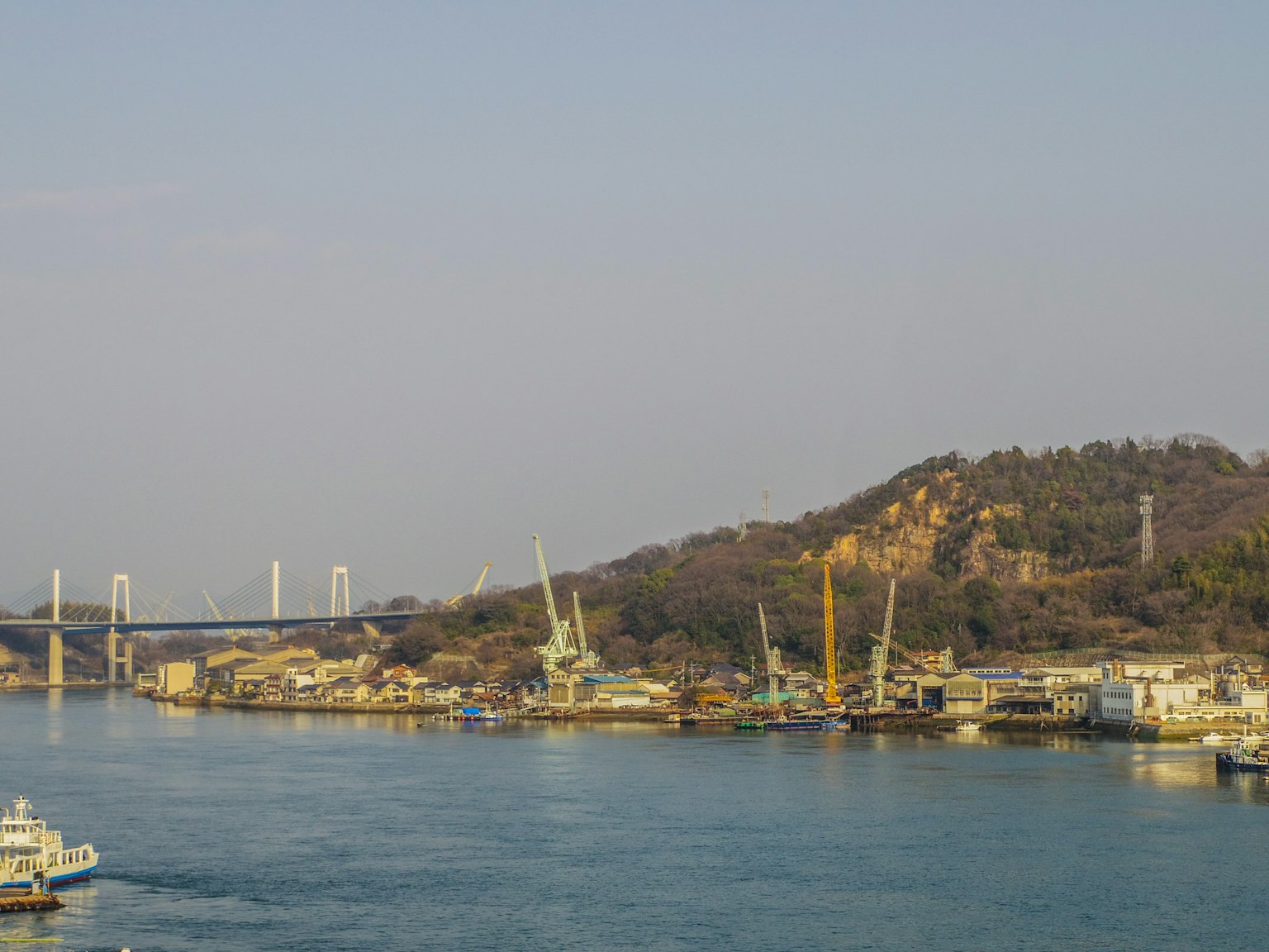 View of a river with cranes and boats along the shore