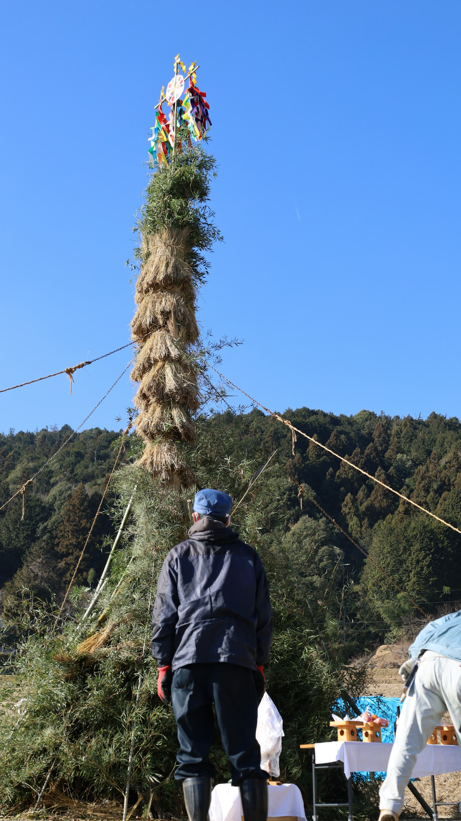 Un hombre mirando hacia una alta torre de hierba bajo un cielo azul claro