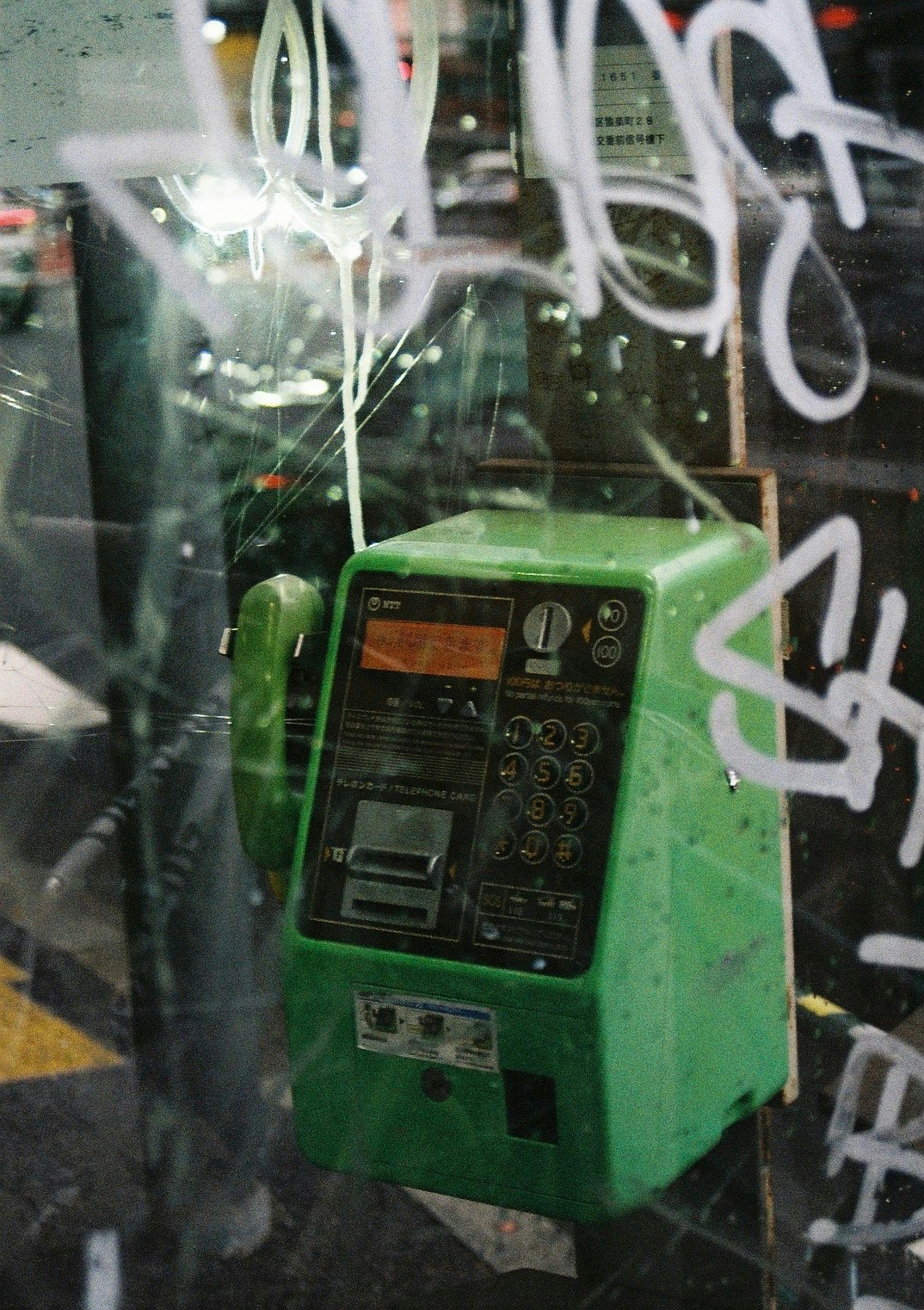 玻璃後的綠色自動販賣機與塗鴉字樣