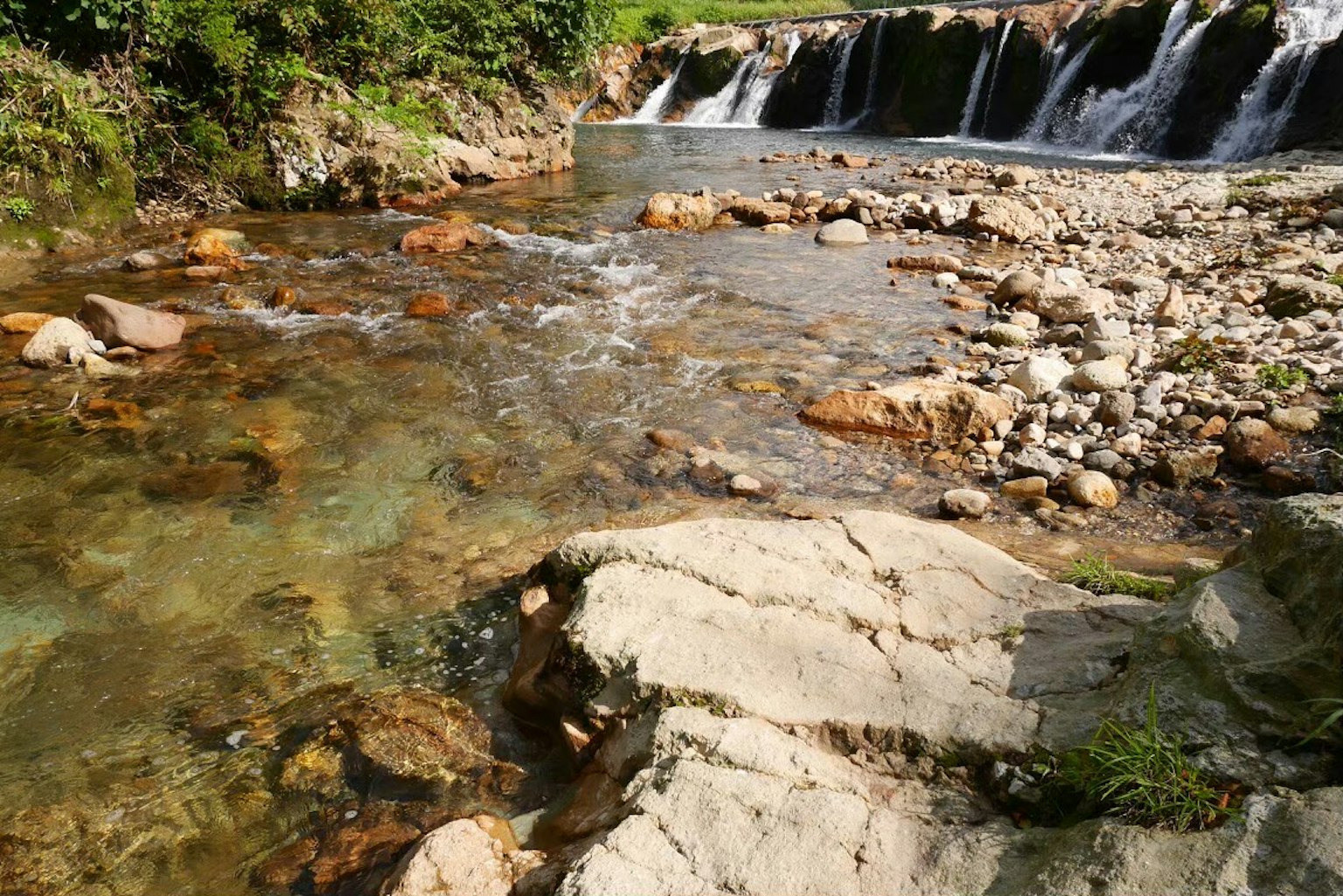 น้ำใสไหลผ่านหินและน้ำตกเล็กในสภาพแวดล้อมธรรมชาติ