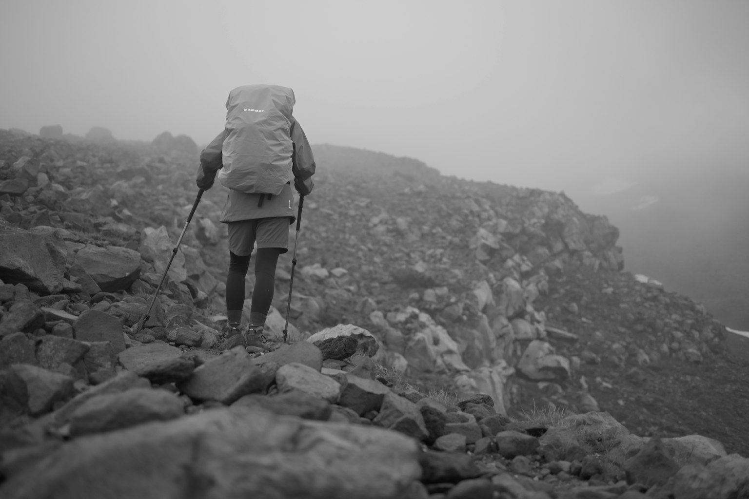 在霧中行走的登山者在岩石地形上