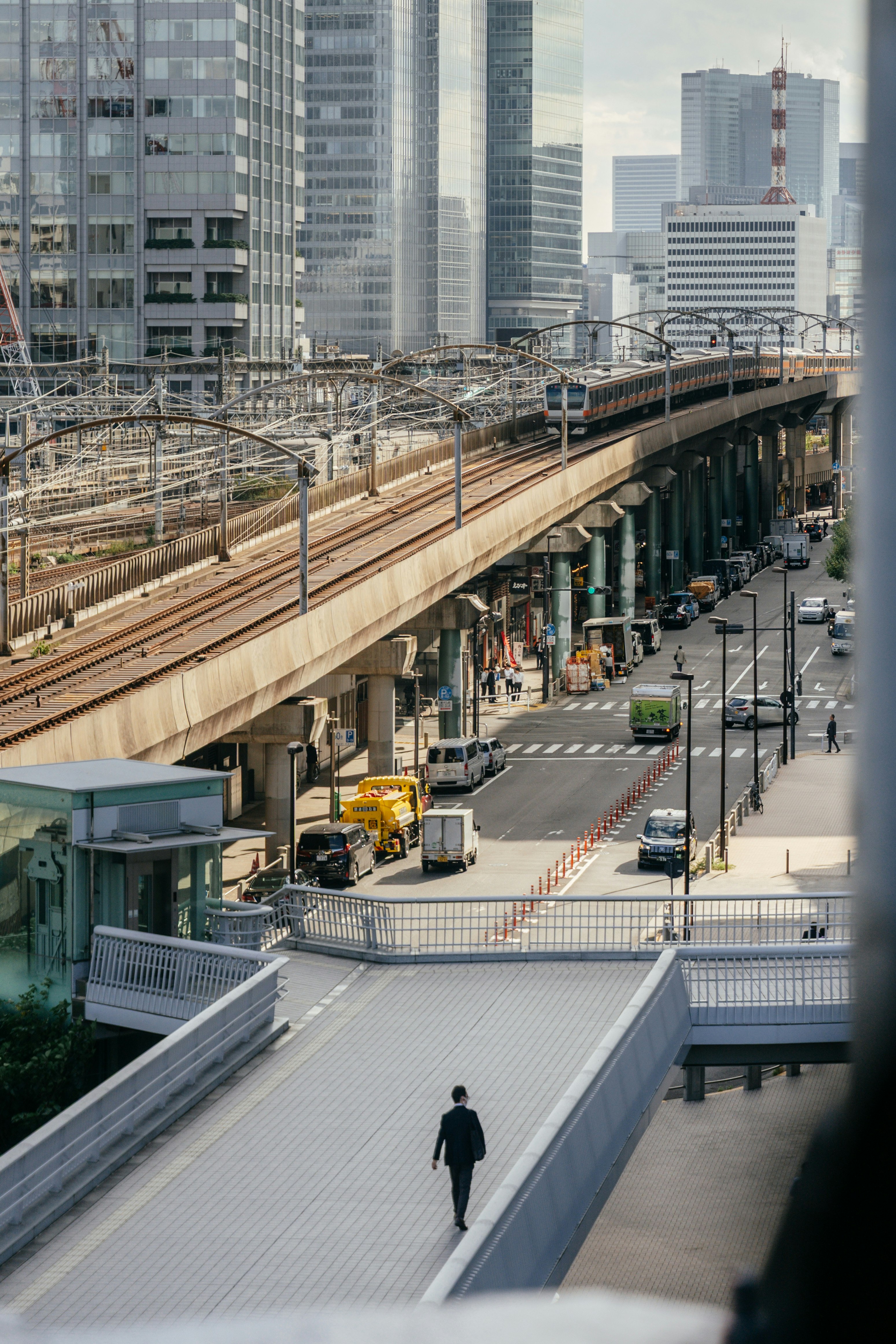 東京の高架線路と駅前の街並みを窓越しに眺める