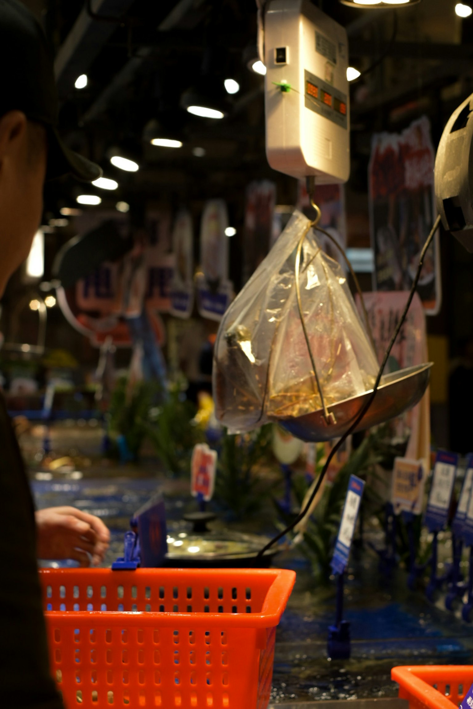 市場で魚を量るためのスケールとオレンジのバスケットが見える