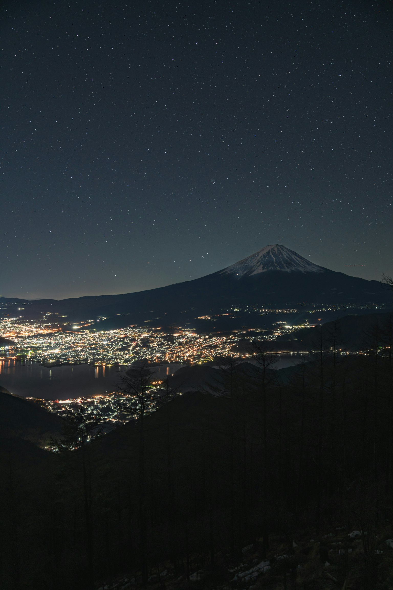 Vista notturna del Monte Fuji con stelle e luci della città