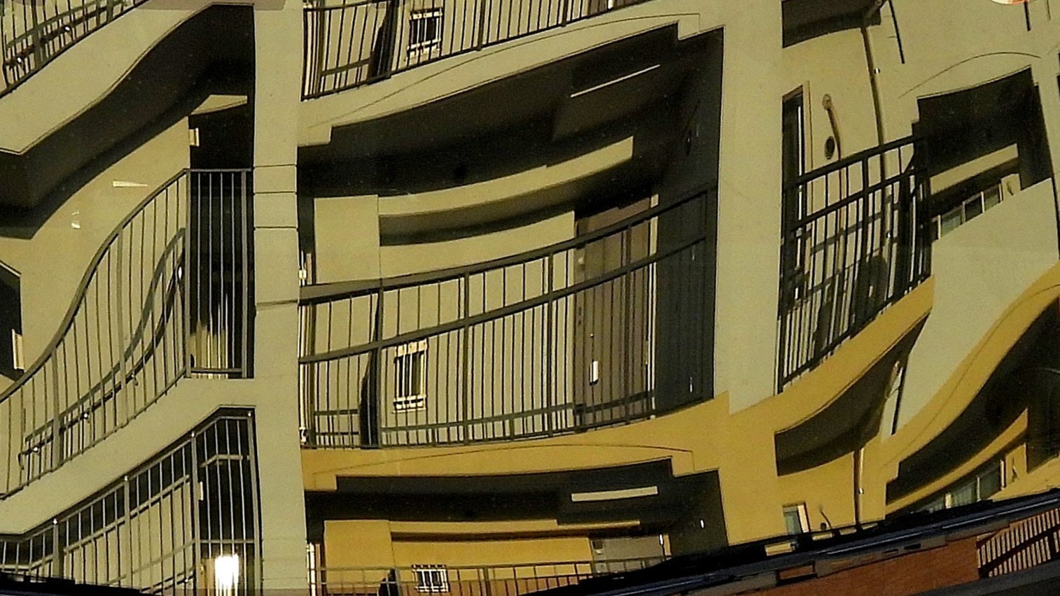 反射する窓と黄色い外壁の建物の中庭