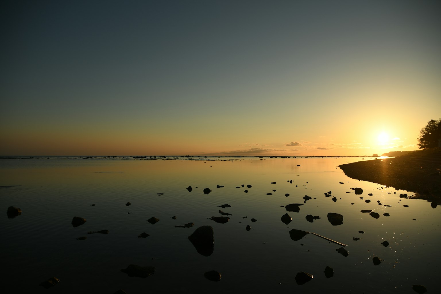 Tranquil sunset over calm waters with rocks