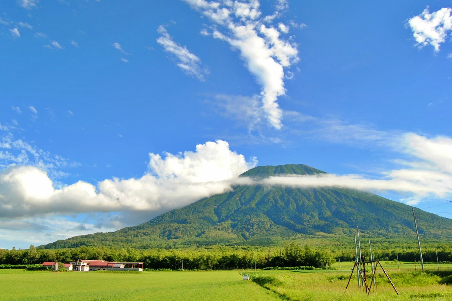 藍天下的山和綠色田野的風景，白雲環繞