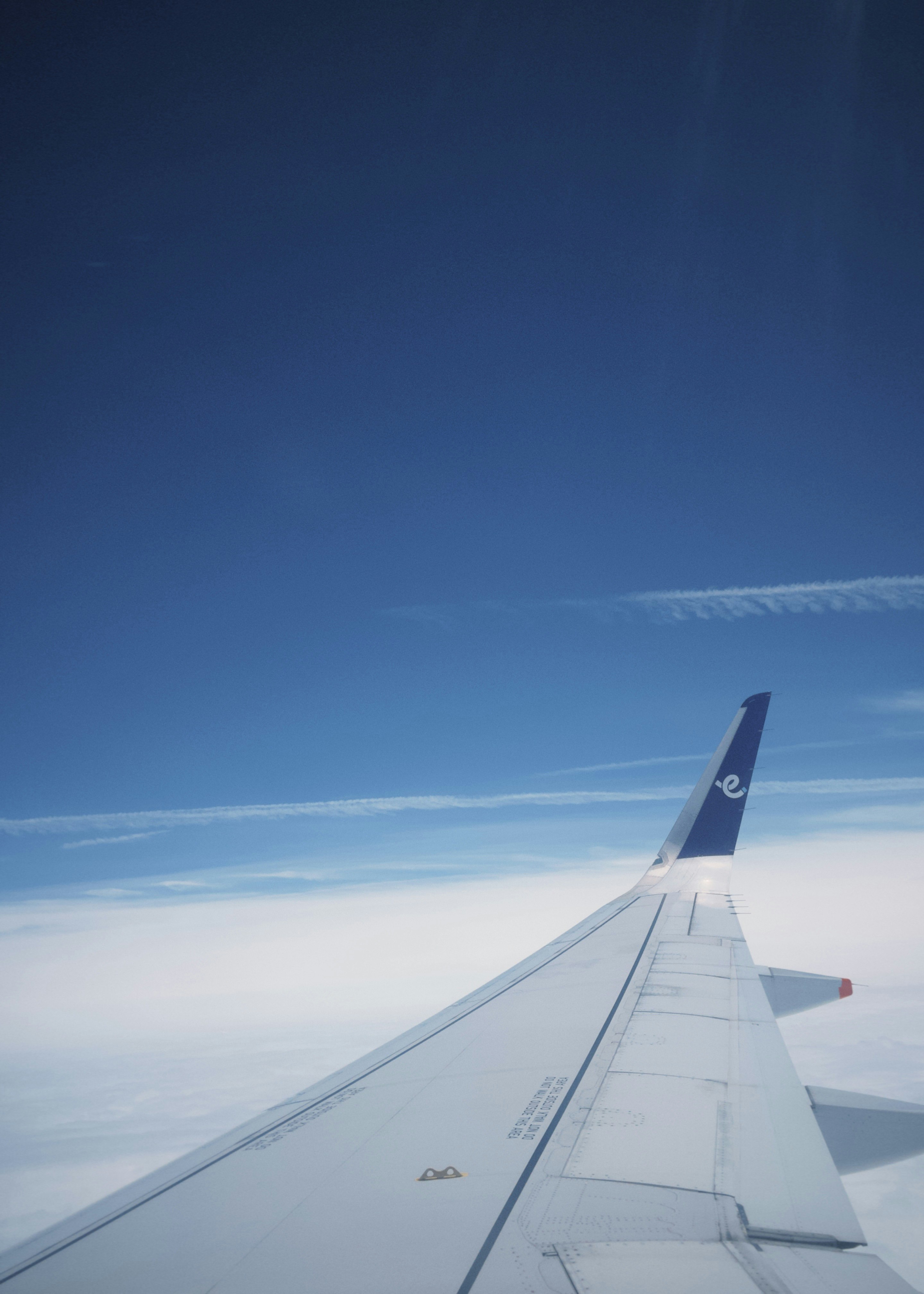 飛行機の翼と青空の雲が広がる機内窓からの眺め