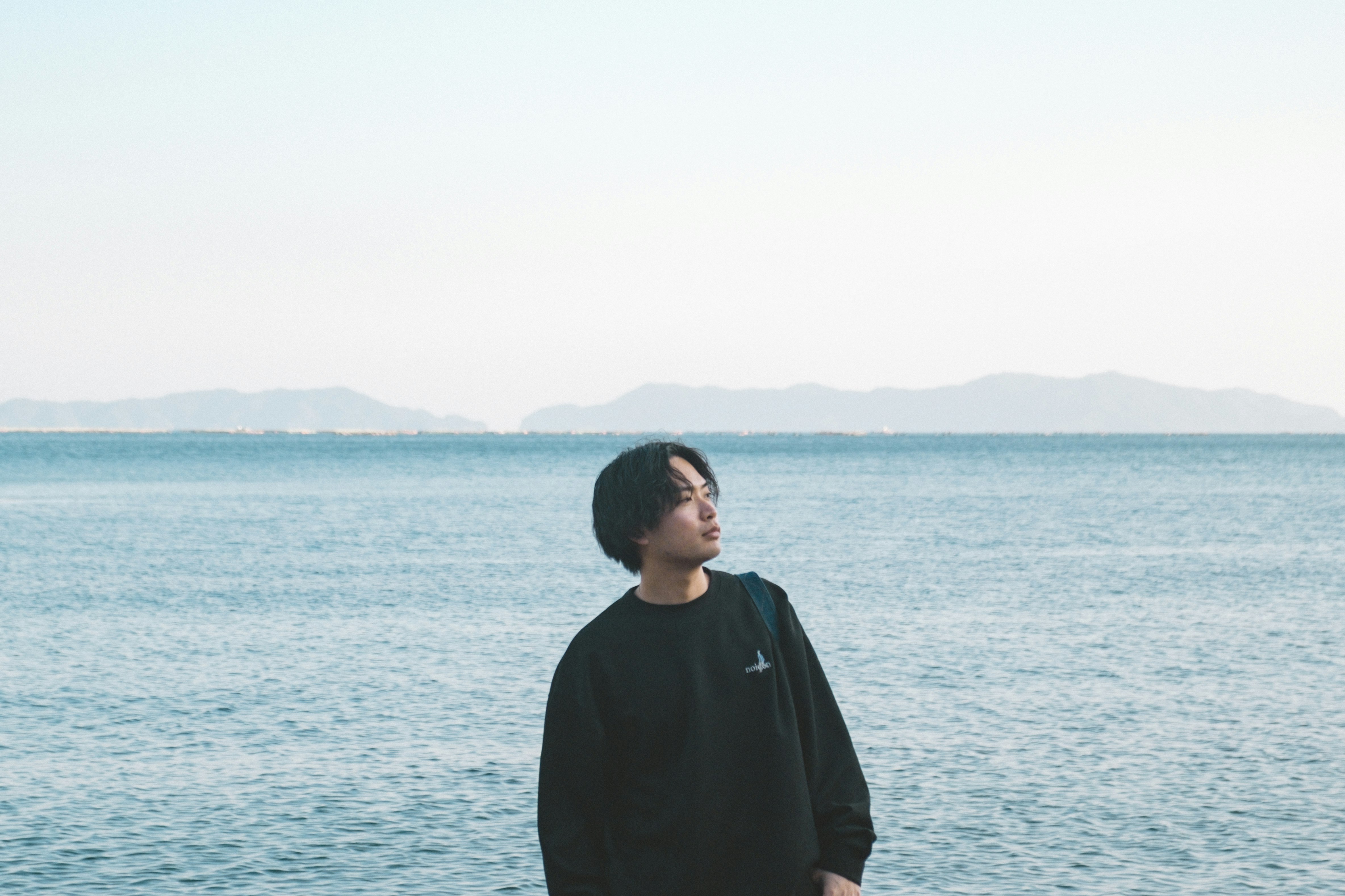 海辺で佇む人物と広がる水平線