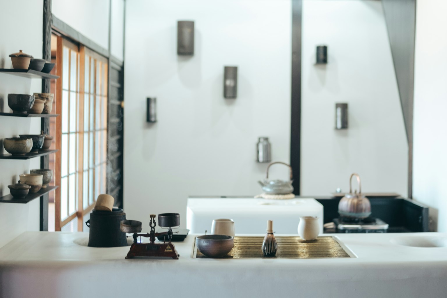 Diseño interior de cocina minimalista con encimera blanca y fregadero negro estantes que exhiben platos de cerámica