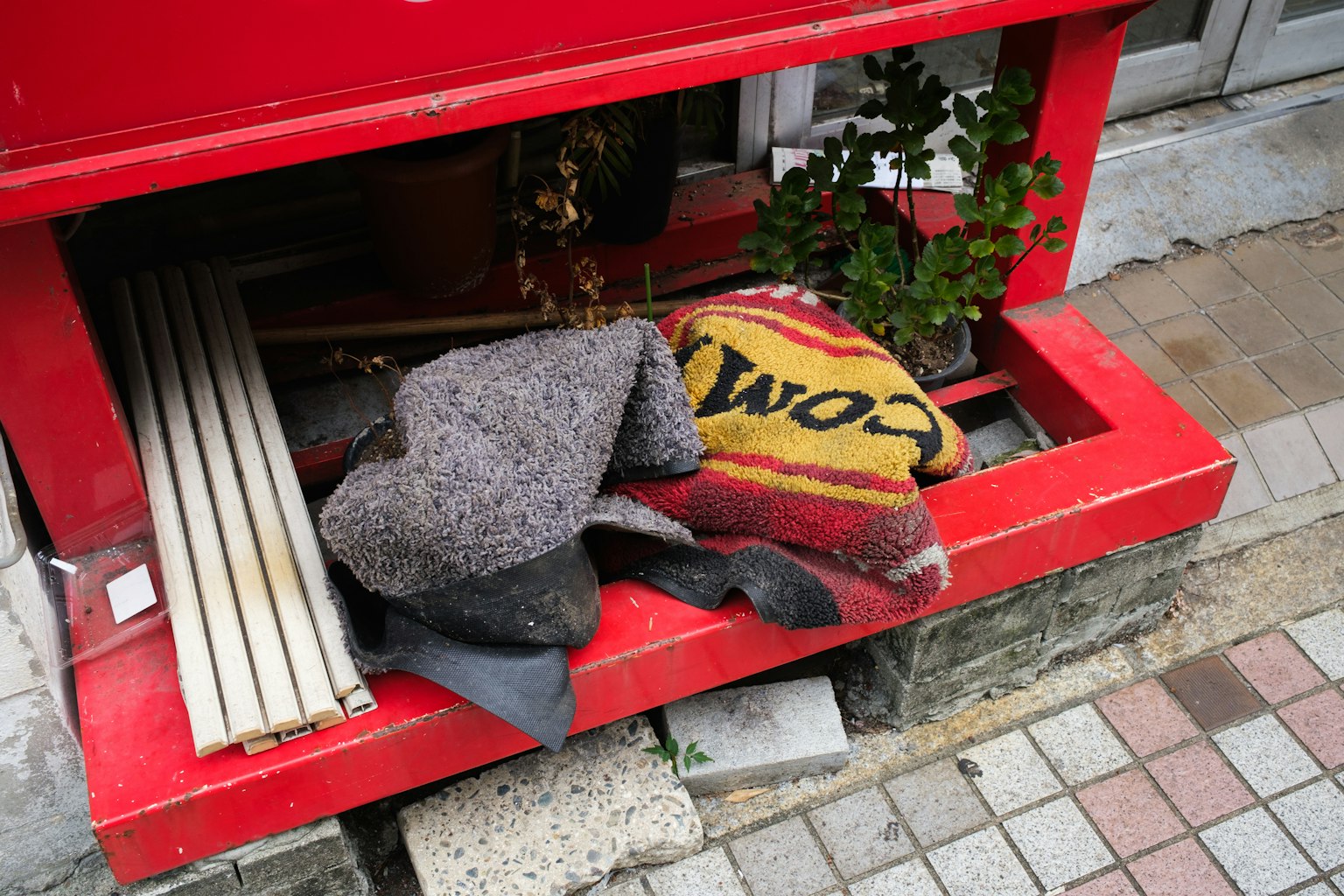 Blankets and plants placed under a red mailbox